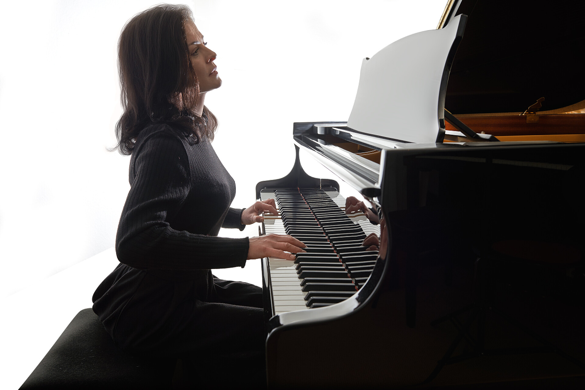 白色背景上弹奏钢琴的音乐家年轻的音乐家弹奏着宏伟的钢琴，在白色背景下孤立的人物形象