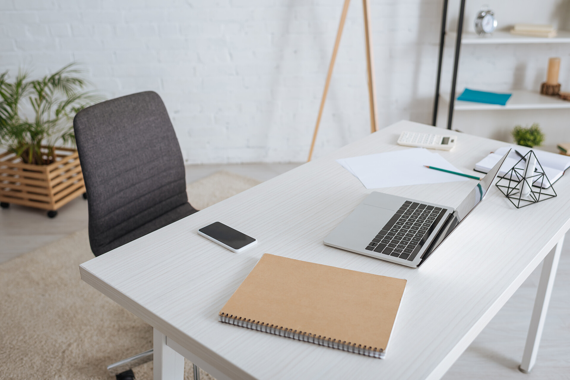 办公室里办公桌上的笔记本记事本智能手机智能手机旁边的笔记本电脑，白色桌子上有空白屏幕 