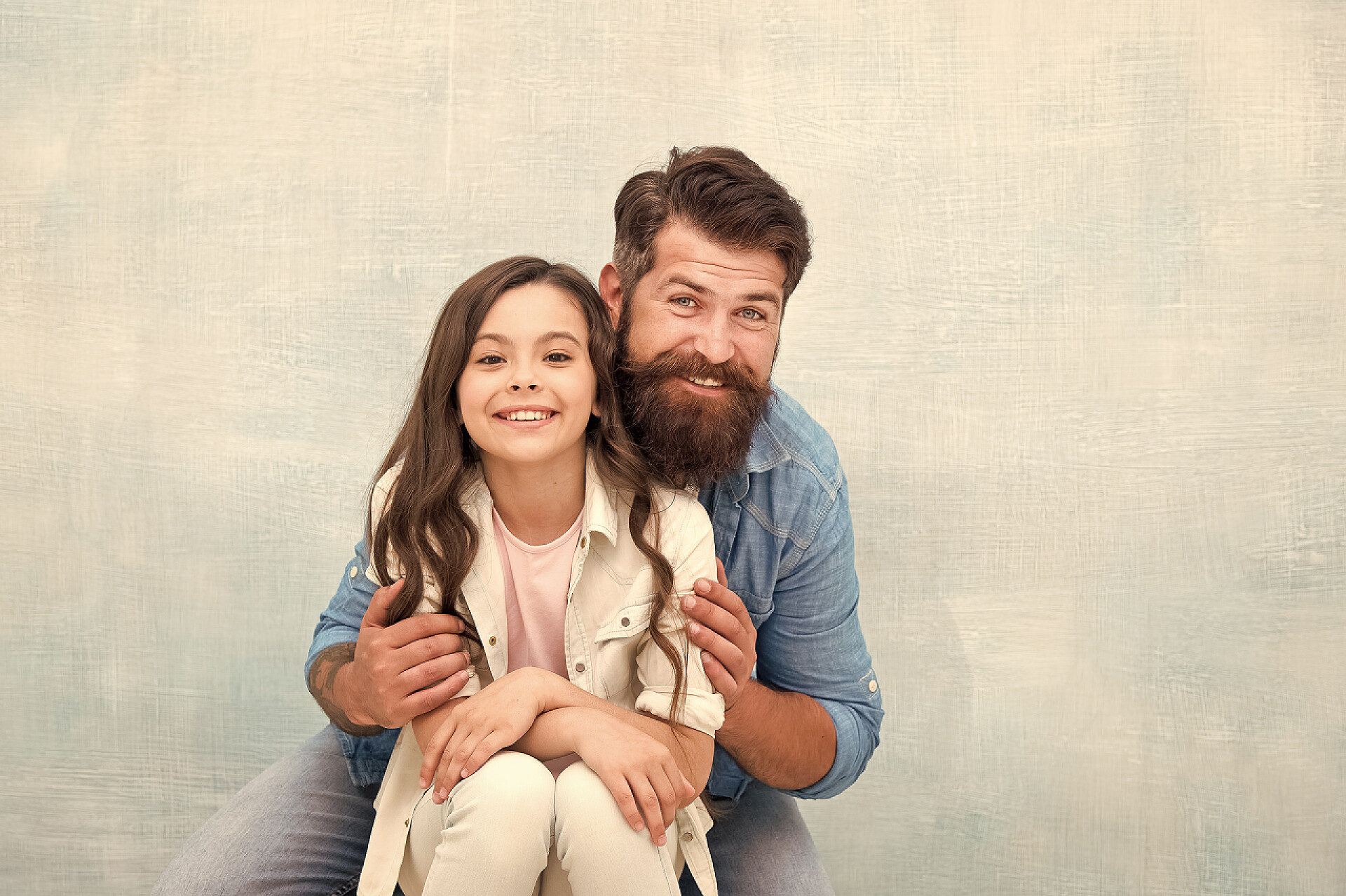 灰色背景中爸爸和女儿开心的拥抱加强父女关系。家人拥抱父亲和女儿拥抱浅色背景。友好关系。父亲节的概念。可爱的父亲和可爱的孩子。孩子和爸爸最好的朋友