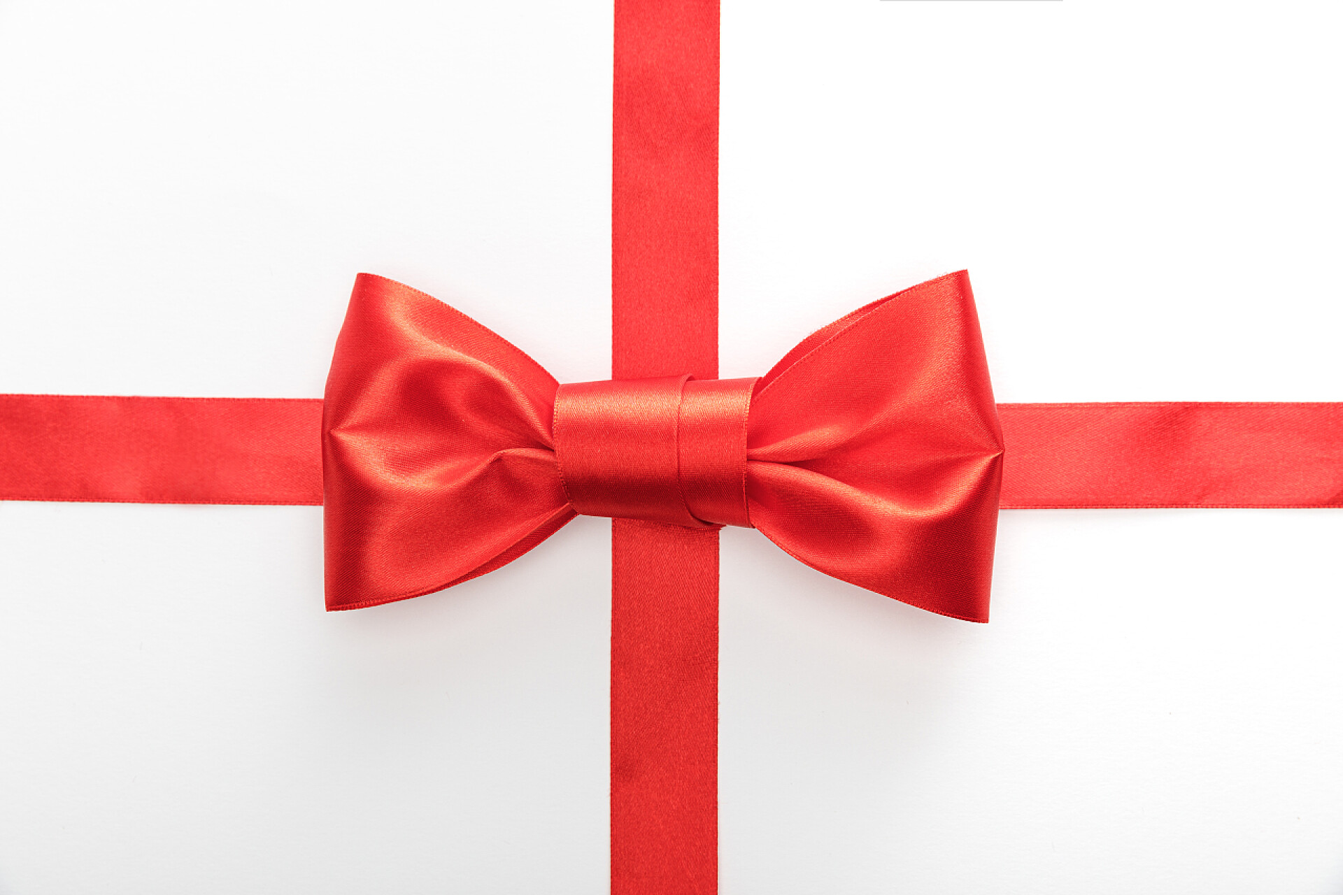 白色背景上红色的礼物盒装饰带红色装饰带的顶部视图，带有白色孤立的弓形图案