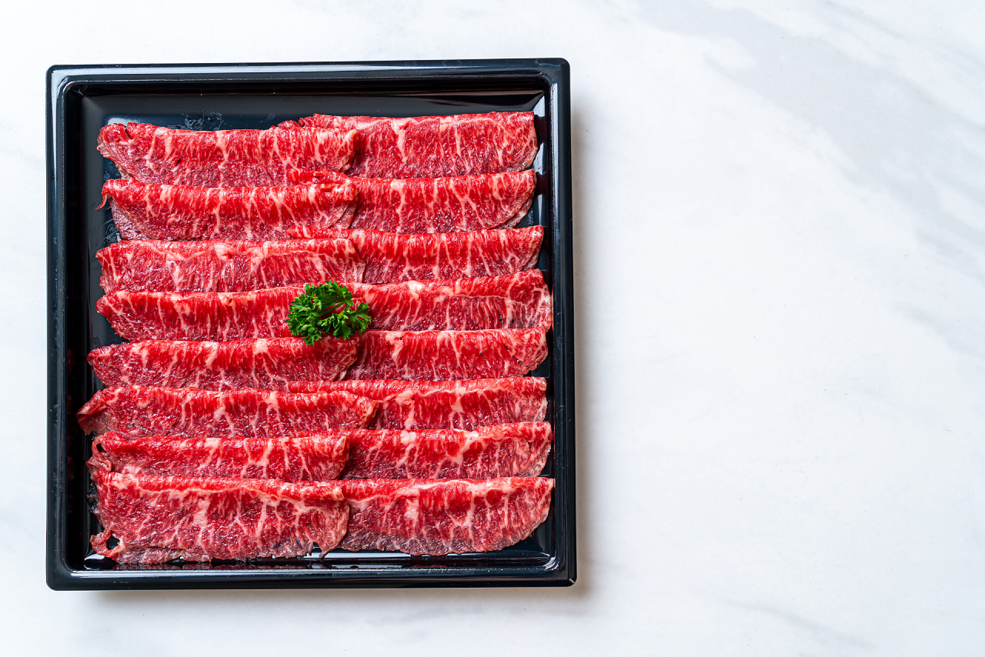 黑色盘子里新鲜的牛肉片新鲜牛肉片，有大理石质感