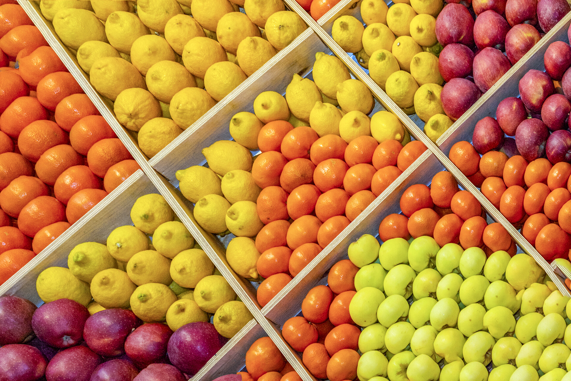 水果市场各种各样的新鲜水果许多不同的水果、柠檬、橘子、橘子都放在盒子里，形成装饰品、图案。从上面看