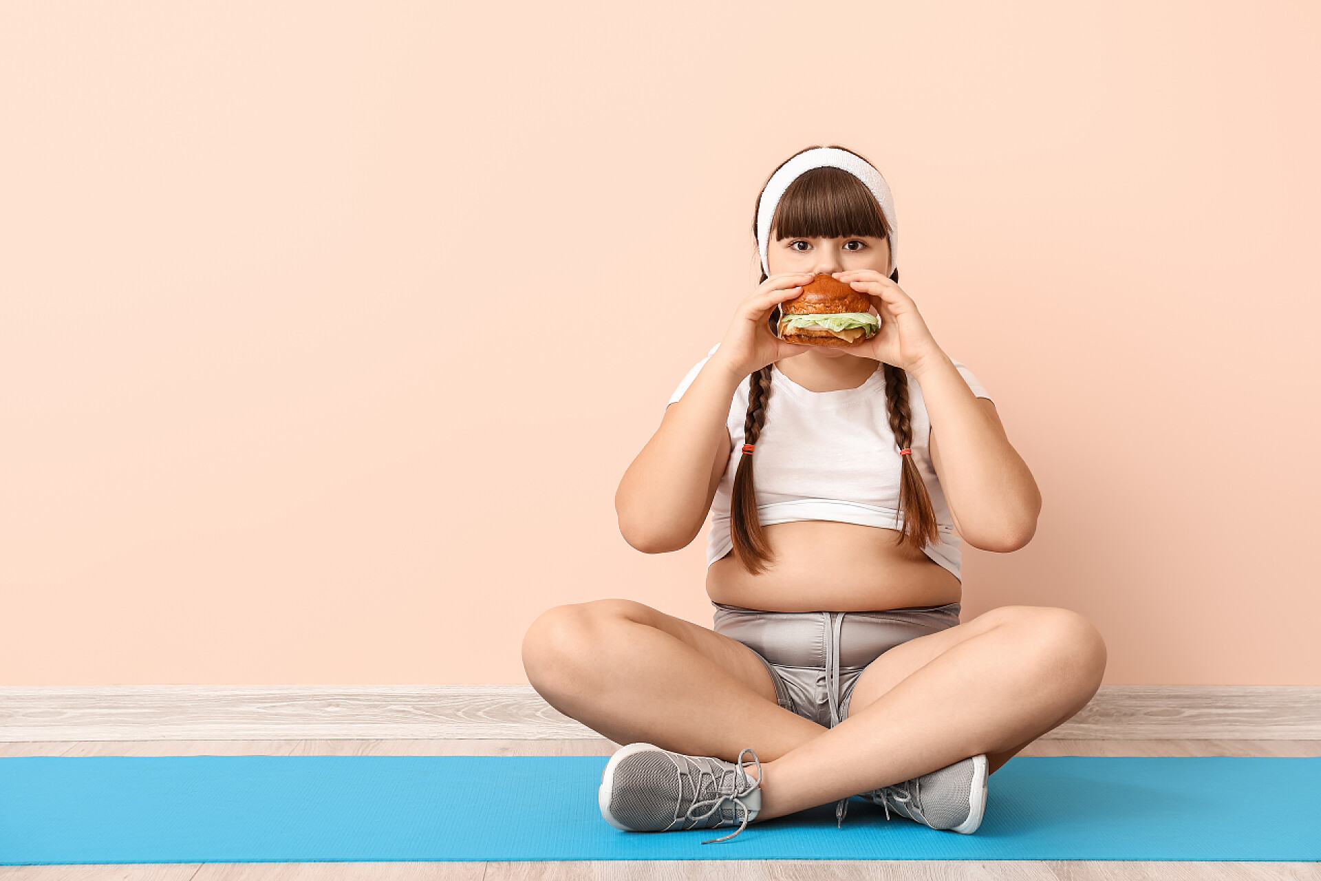 一个超重的胖女孩在吃汉堡包体重超标的女孩在彩墙附近吃着不健康的汉堡包