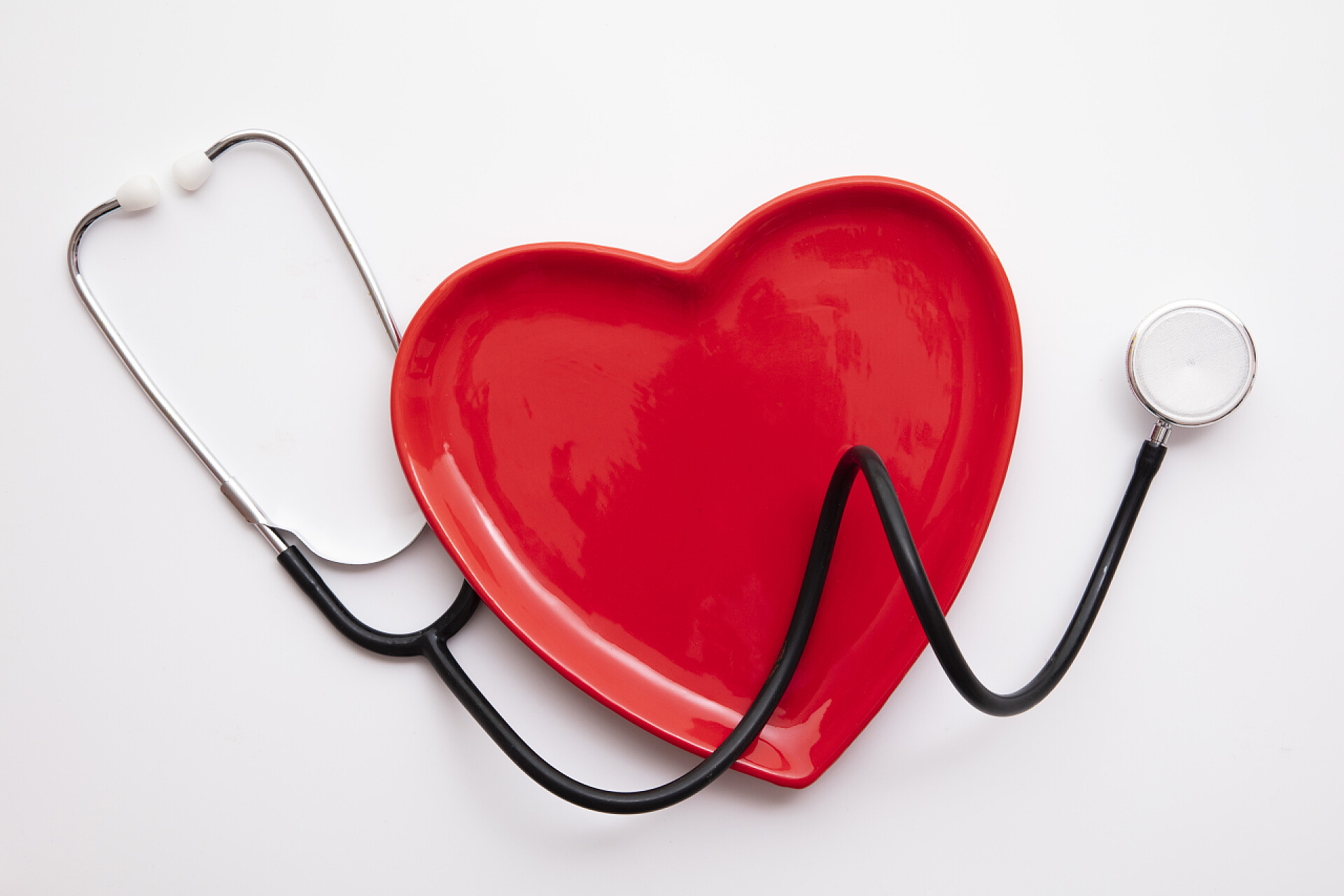 灰色背景上红色爱心听诊器带听诊器的红心形状。健康的心脏概念