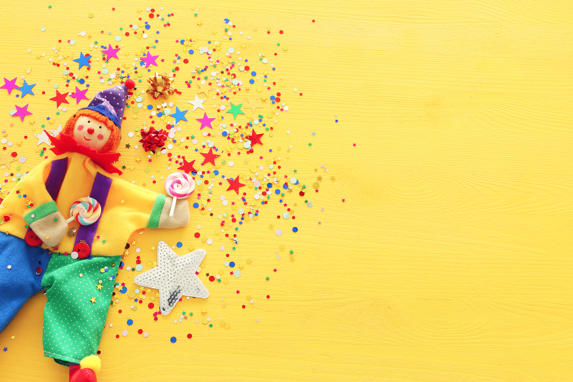 黄色背景上的布偶玩具派对五彩斑斓的噪音和可爱的小丑在黄色的木制背景之上.俯瞰，平铺