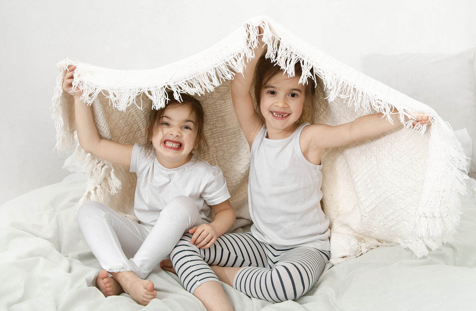 两个可爱的妹妹顶着毛毯两个可爱的妹妹抱在卧室的床上.