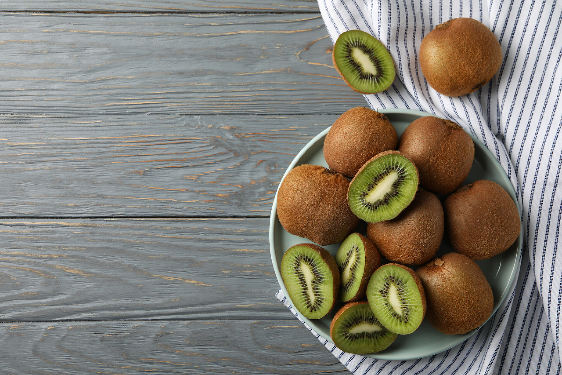 桌上放置的猕猴桃木制背景的成熟猕猴桃盘，顶部视图