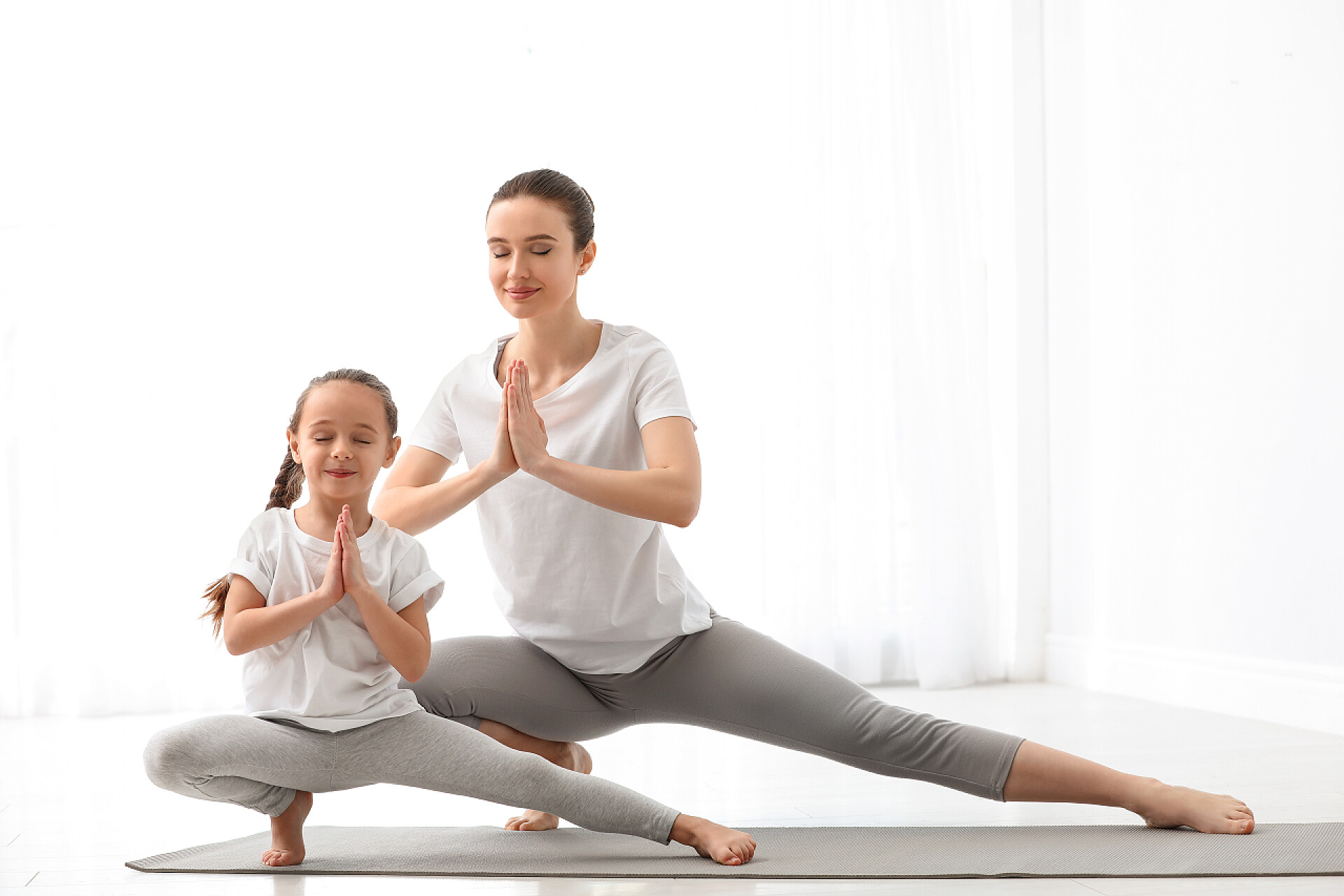 在家里练瑜伽的母女小女儿在家里练瑜伽的年轻妈妈