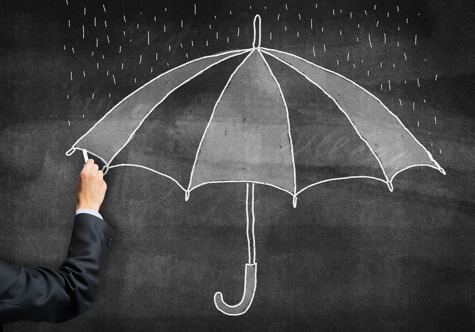 手拿粉笔在黑板上画了一把伞商人手拿粉笔在黑板上画了一张伞形草图.黑板上的手工插图。公共保险计划广告.防止各种生命和经济风险.
