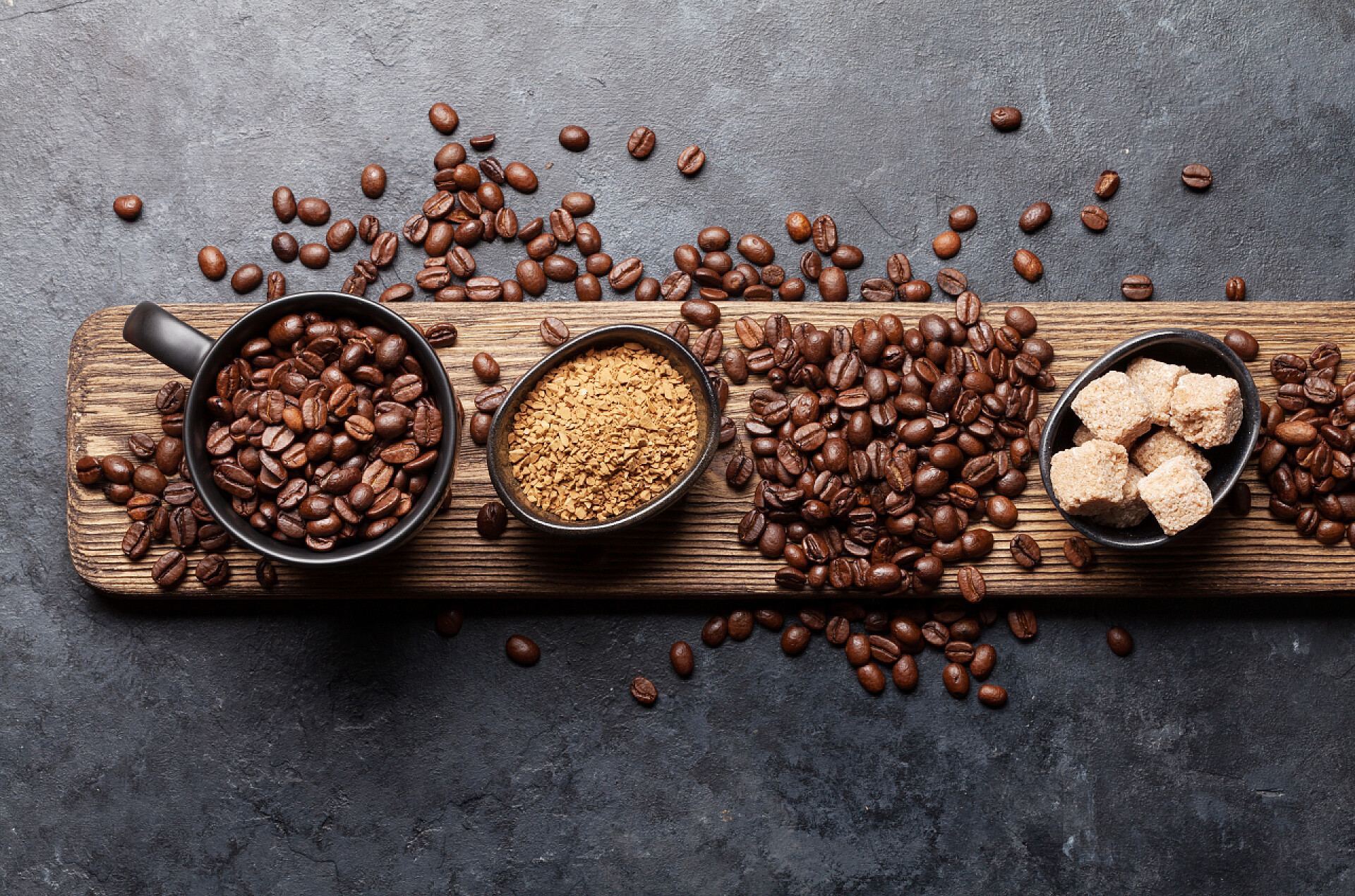 桌子上的咖啡豆豆子咖啡杯、糖和烤豆放在深色石桌上.顶部视图。平躺在床上