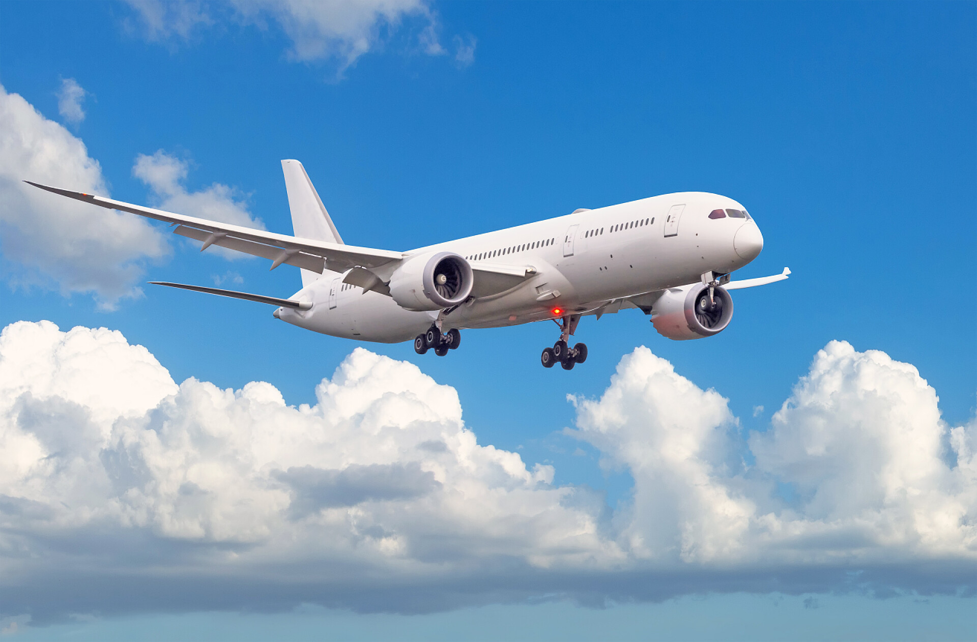 蓝天白云下飞翔的飞机带着起落架的客机在机场登机前降落在云层和蓝天的背景下