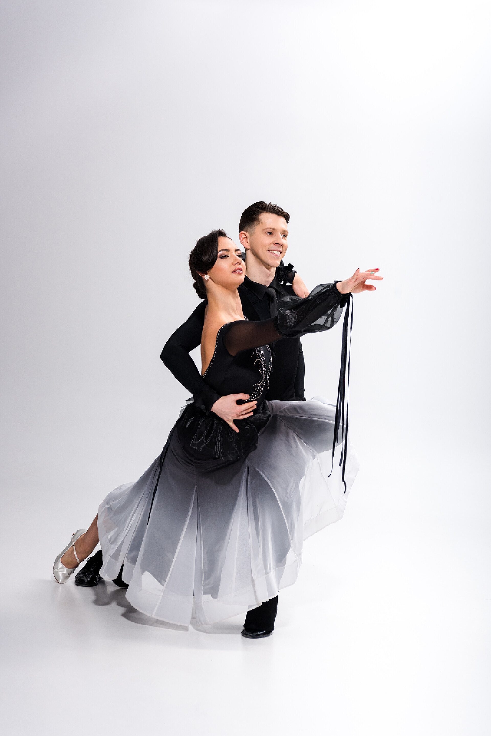 灰色背景上穿着黑色服装跳舞的舞者穿着黑色服装的年轻貌美的一对舞女在白衣上跳舞