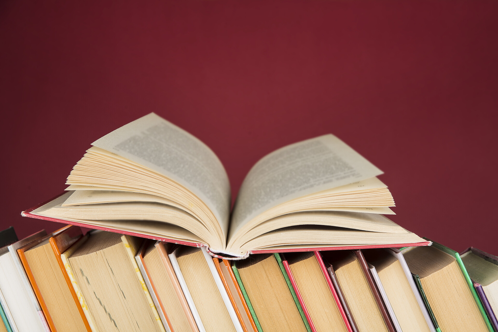 红色背景上的书堆和打开的书一堆五颜六色的书教育和娱乐概念