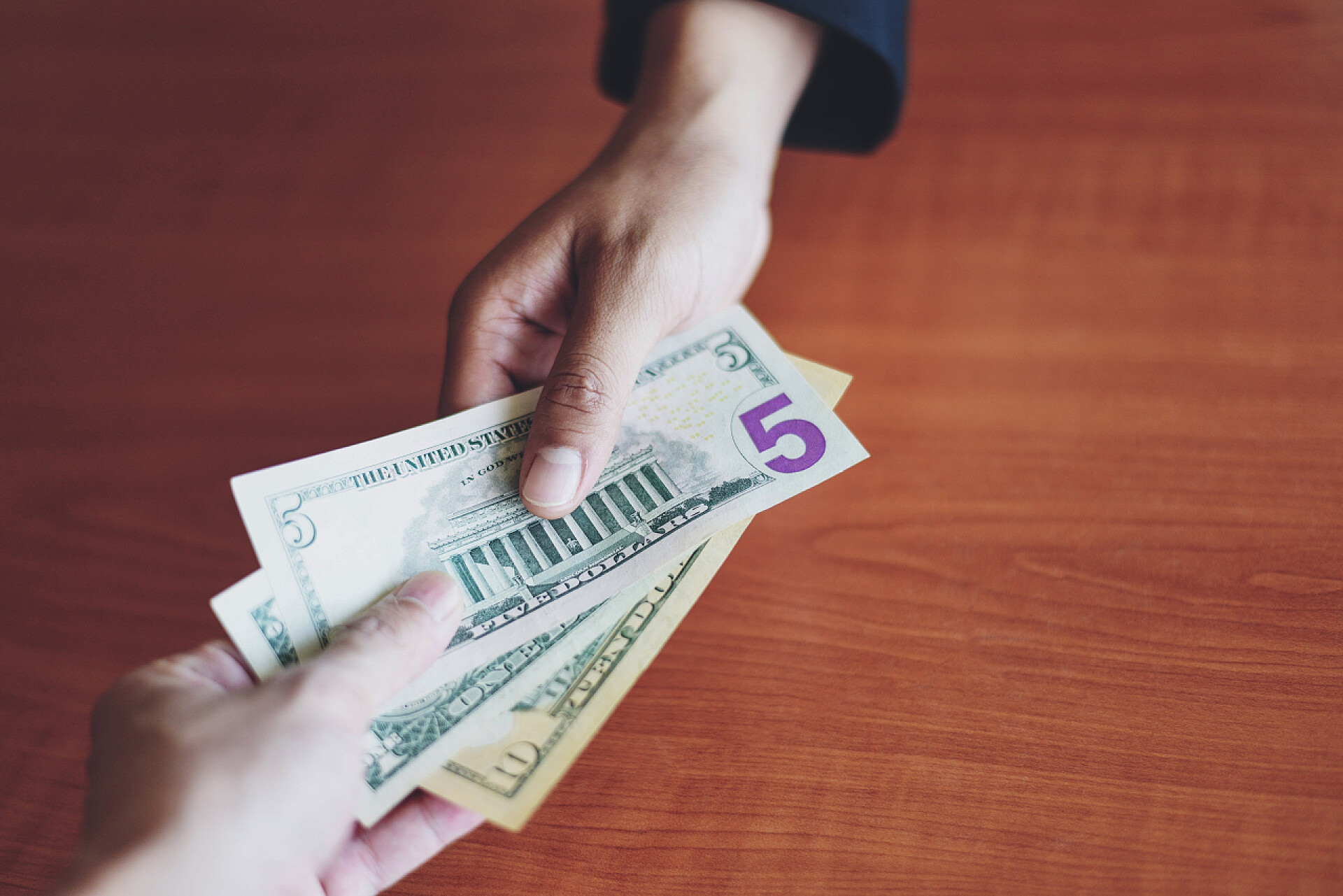 相互交换钱币特写镜头Business man give money bribe concept / person hands man giving money on wooden table background pay cash on delivery pay to receive money  