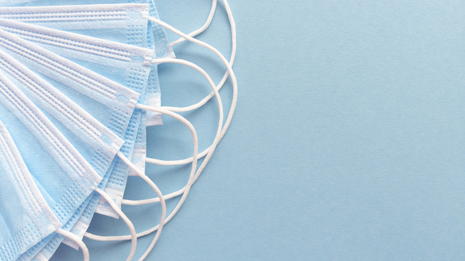 医用口罩扇形布置在蓝色背景的左边医用口罩扇形布置在蓝色背景的左边.简单的平面与复制空间。医学概念。库存照片.