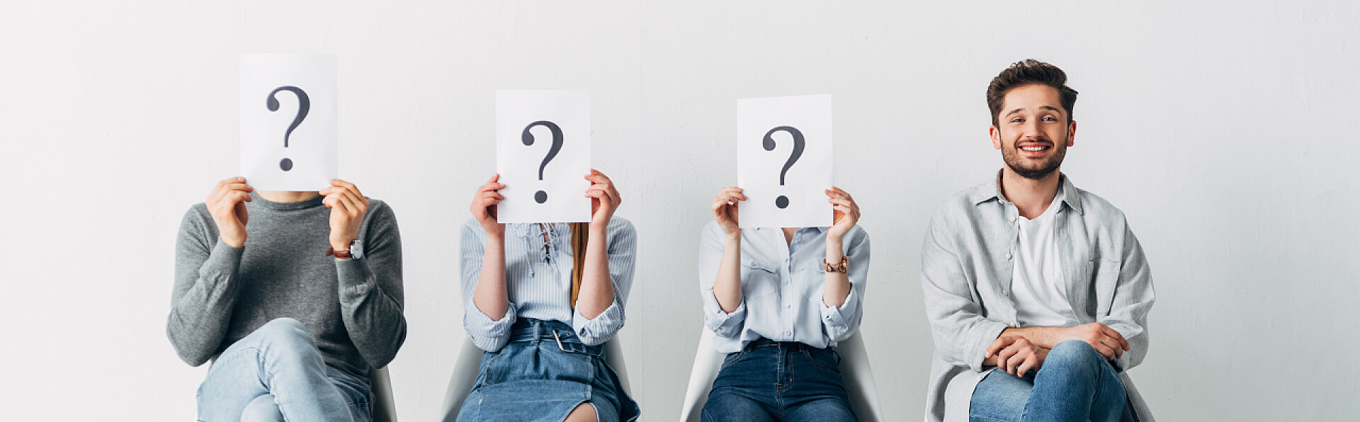 面带微笑的男人和拿着刻有问号的卡片的员工全景照片，面带微笑的男人拿着刻有问号的卡片在员工身边看着相机