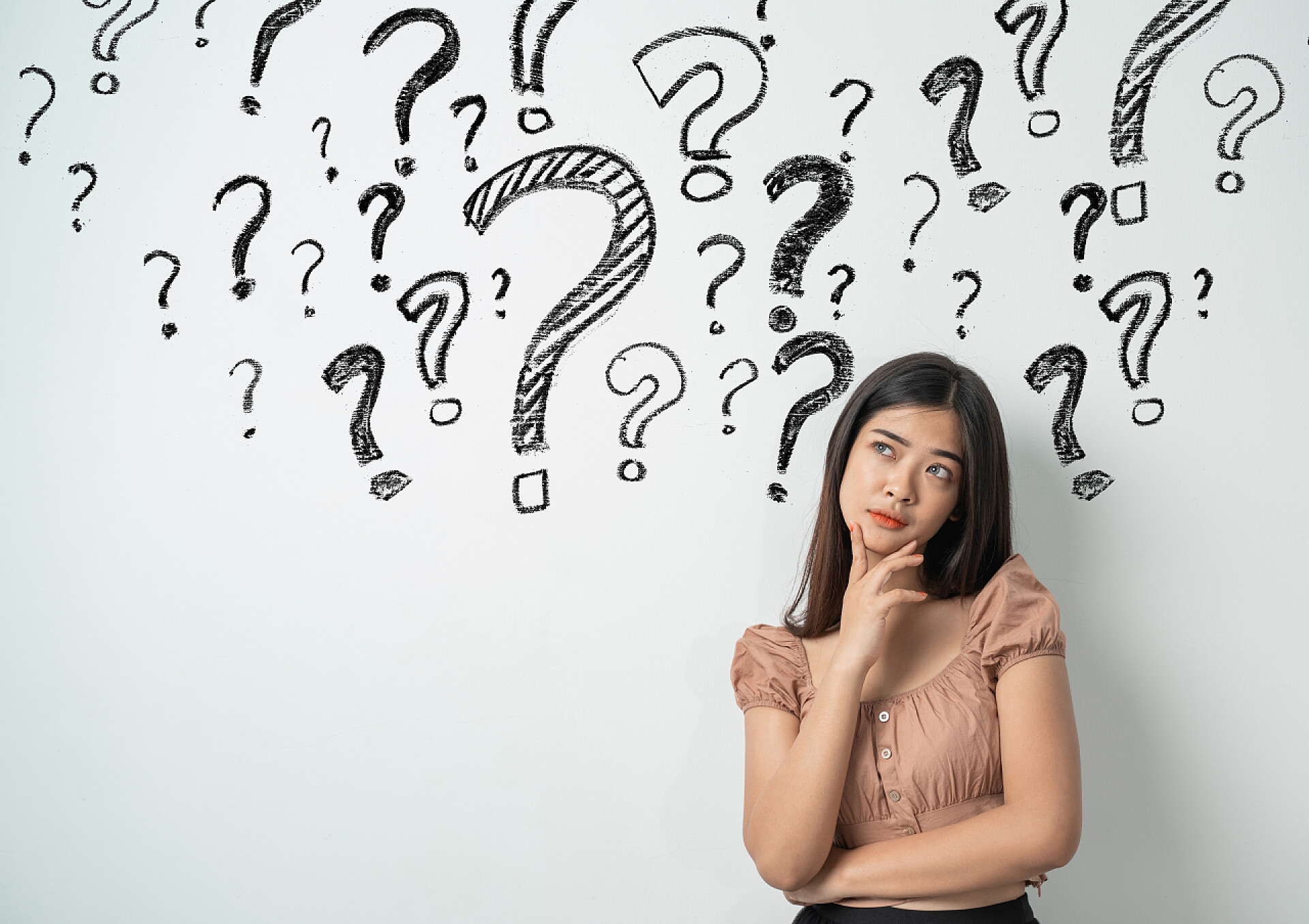 灰色背景上有问号的年轻妇女有问号的妇女