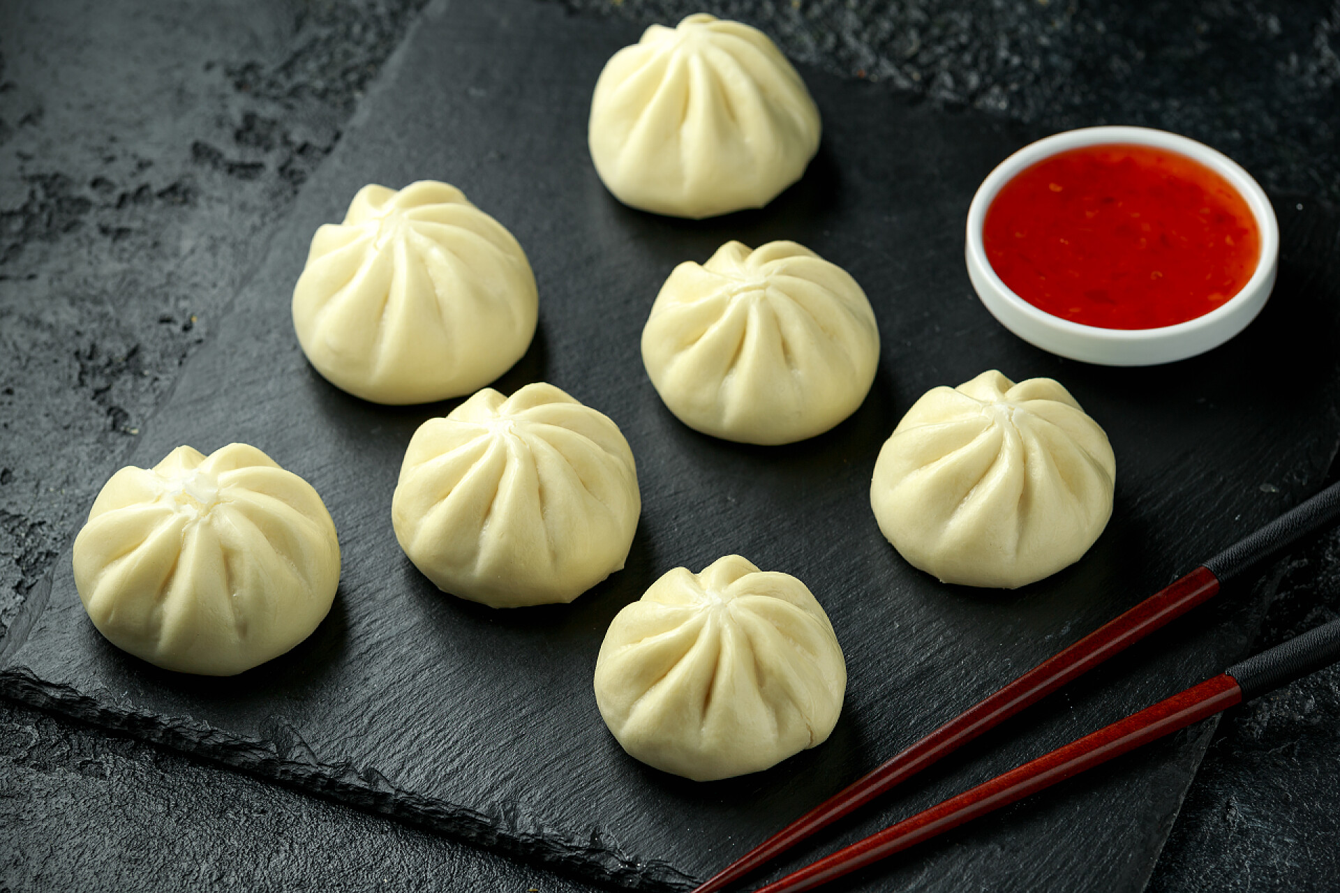 乡村石板上摆放的蒸包与辣椒酱蒸包与鸭馅，辣椒酱在乡村石板上。亚洲食品