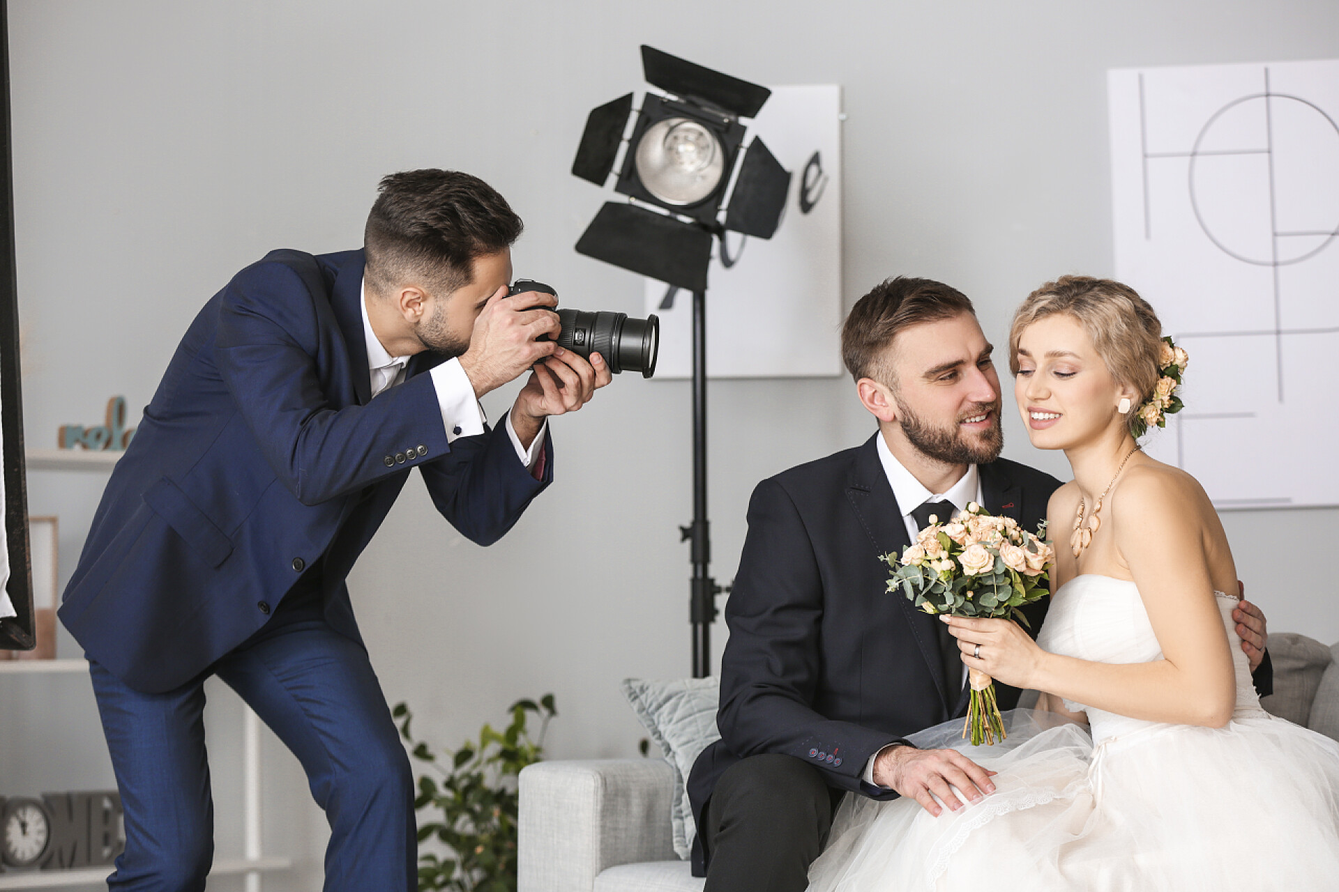 摄影师在给一对新婚夫妇拍结婚照Photographer working with young wedding couple in studio
