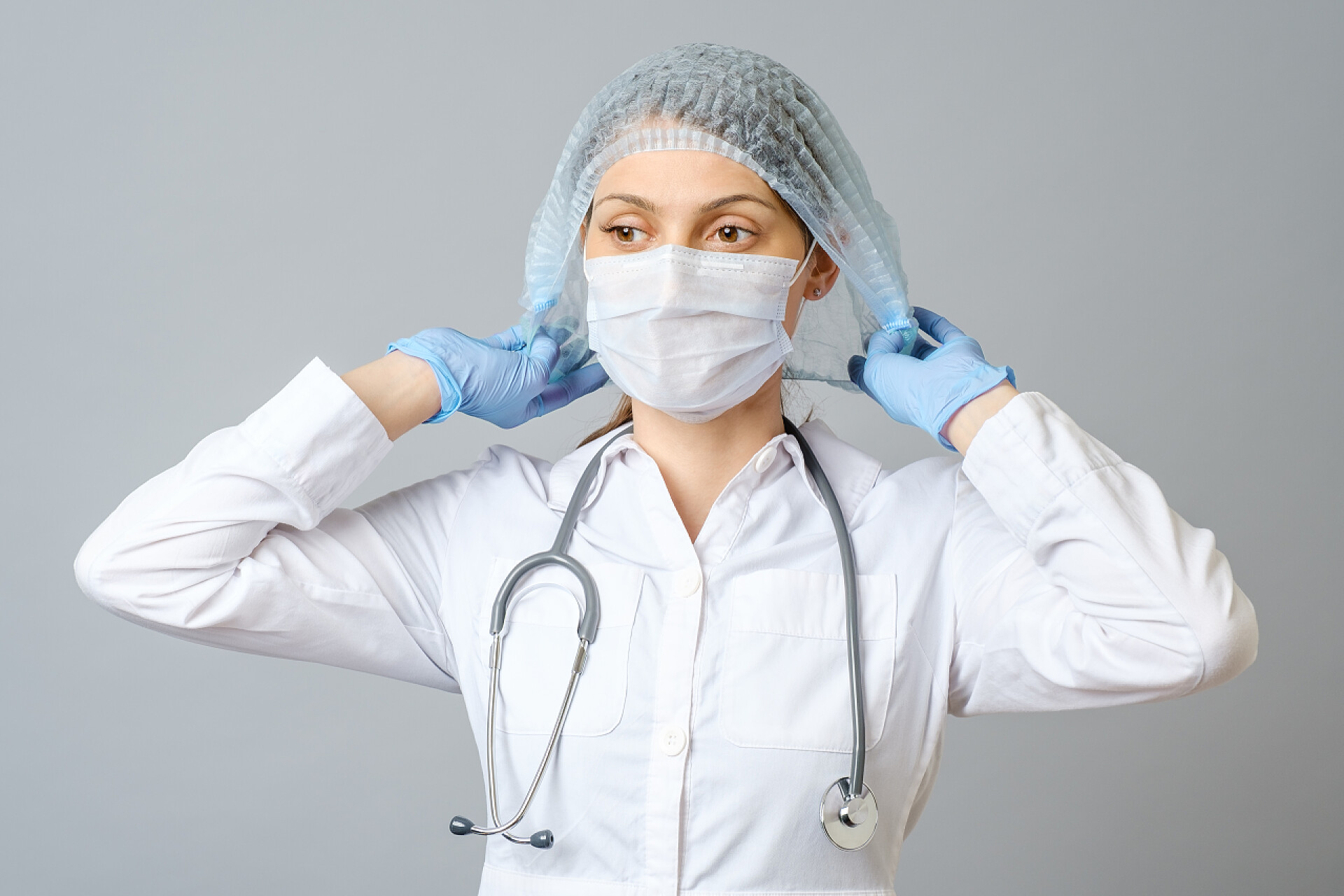 灰色背景上的头戴灰色防护帽的女医生头戴灰色防护帽的女医生或护士