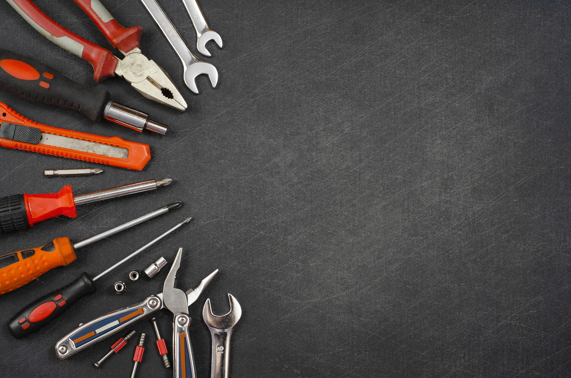 黑色背景上一套工具一套不同的红色工具，包括锤子扳手钳，螺丝刀，纸刀，螺丝刀喷嘴，黑色背景的钥匙 