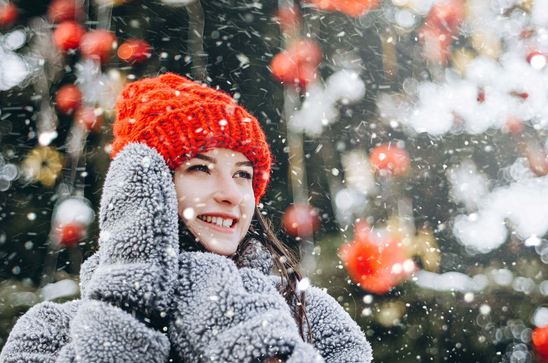 公园里圣诞树下的年轻女子在雪地覆盖的公园里，一位身穿生态皮毛和手套的年轻漂亮女子站在圣诞树前的肖像。快乐的新亚雅概念。复制空间