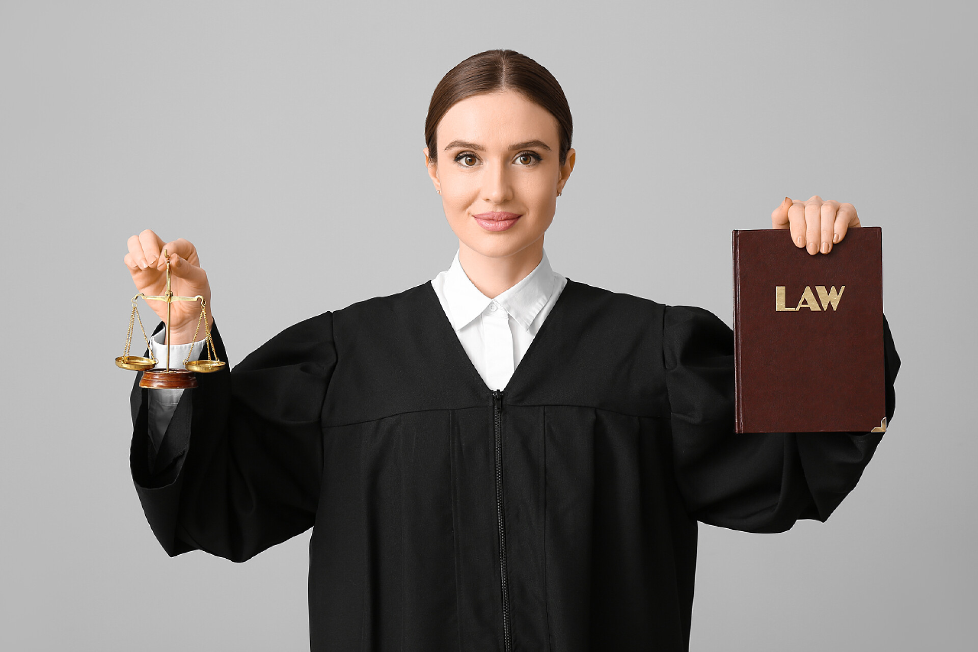 灰色背景上手拿书籍和公平秤的女人具有轻背景的书籍和公正尺度的女法官