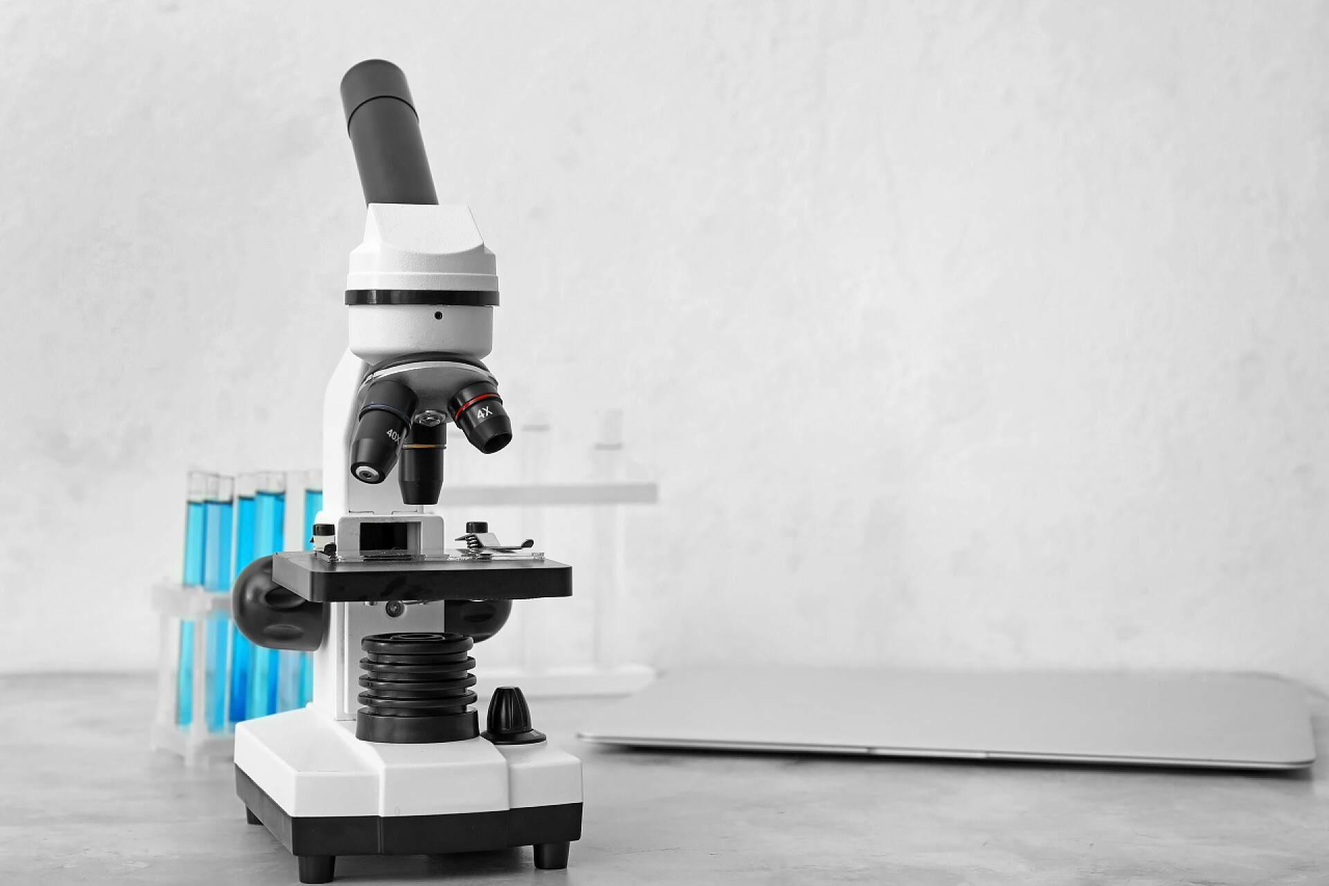 桌子上摆放的化学仪器现代显微镜、试管和笔记本电脑放在桌上