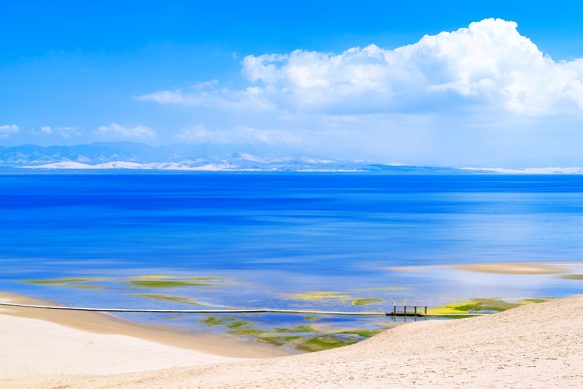 蓝天白云下的青海省青海湖沙洲风景中国青海省青海湖沙洲上的白垩。沙漠和无尽的蓝湖