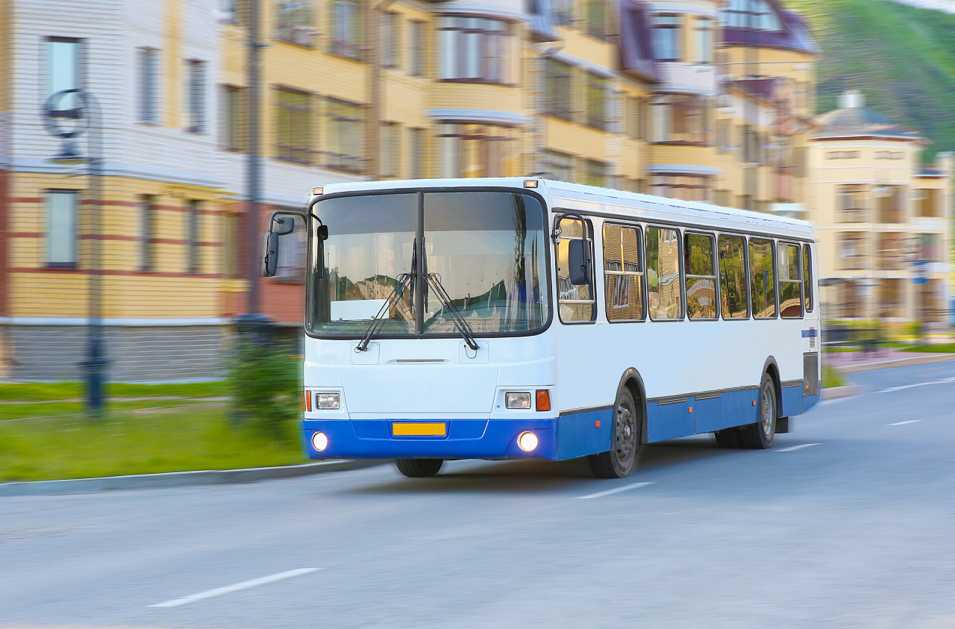 在道路上行驶的公共汽车白色城市的公共汽车沿街行驶