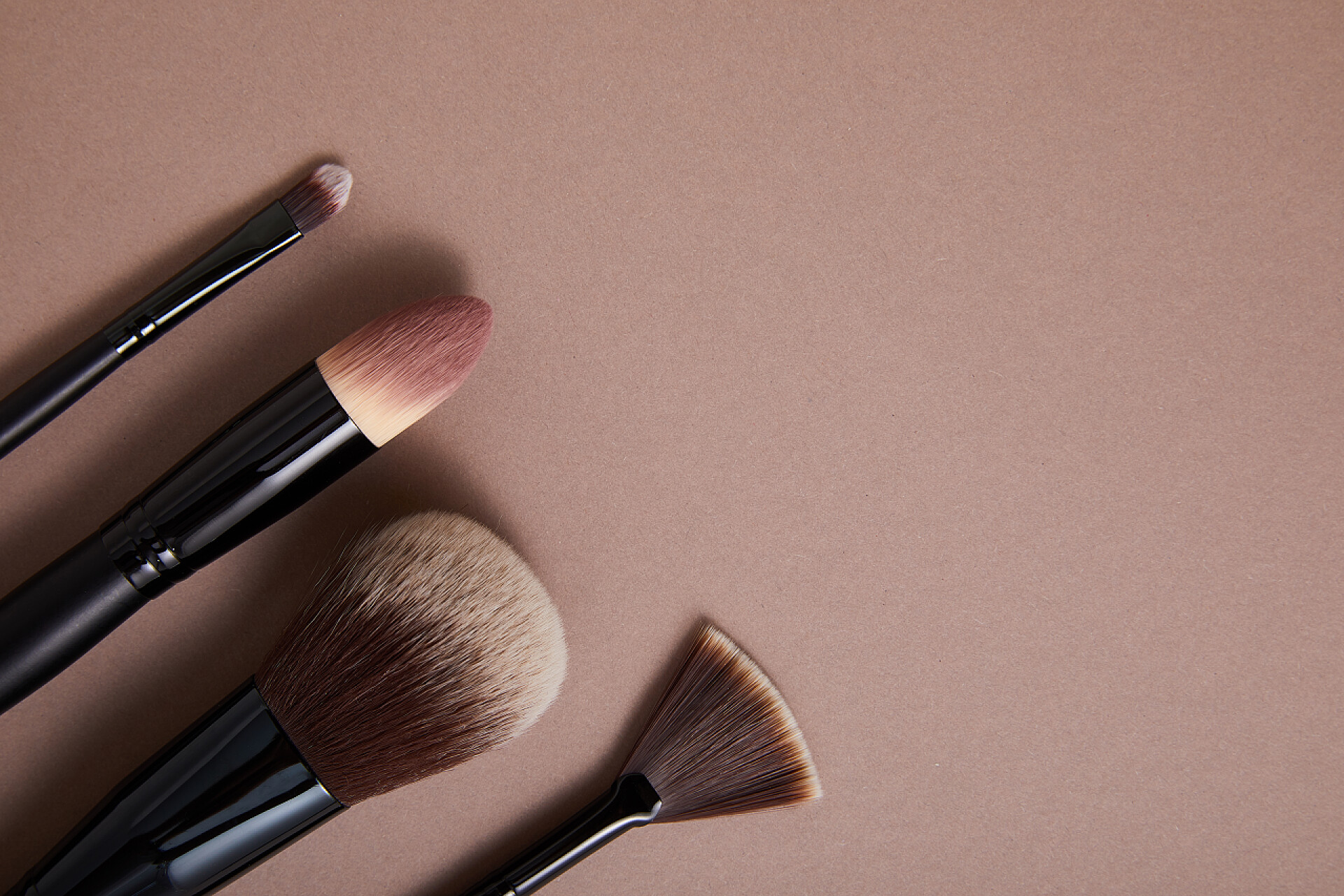 棕色背景上的化妆刷一套具有米色背景、近视、美感的专业化妆品刷 
