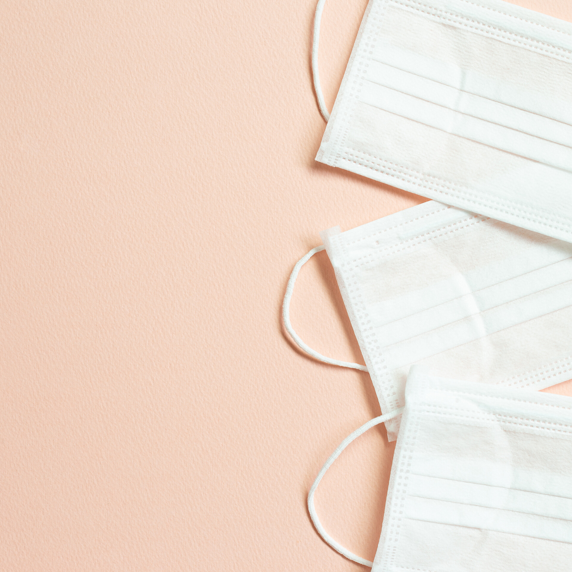 粉色背景上的口罩粉色背景的医疗面罩。简单，极小