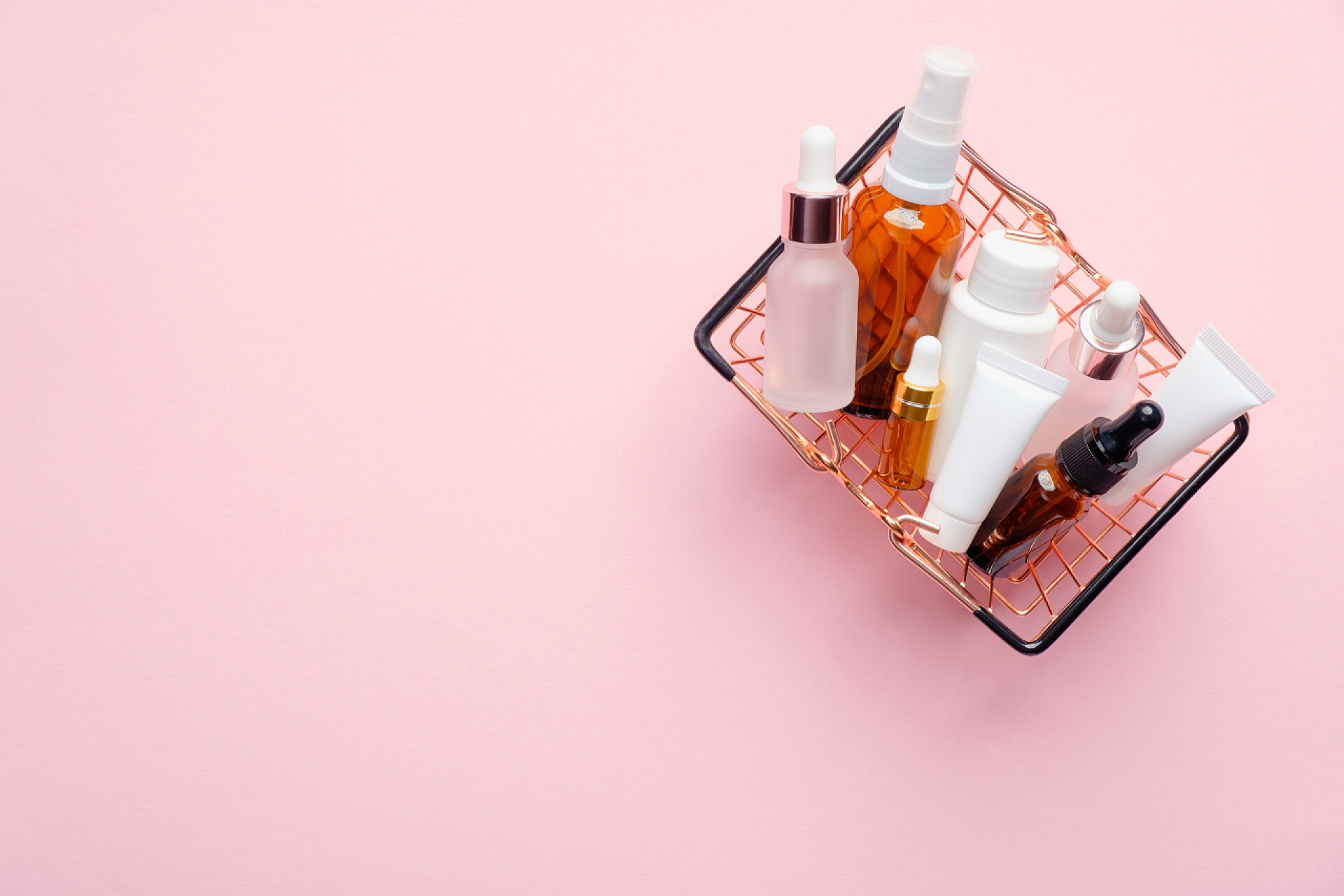 粉色背景上的化妆品用粉色底色的天然有机化妆品购物篮。美容店打折销售横幅模型.平躺在地上，俯瞰四周.