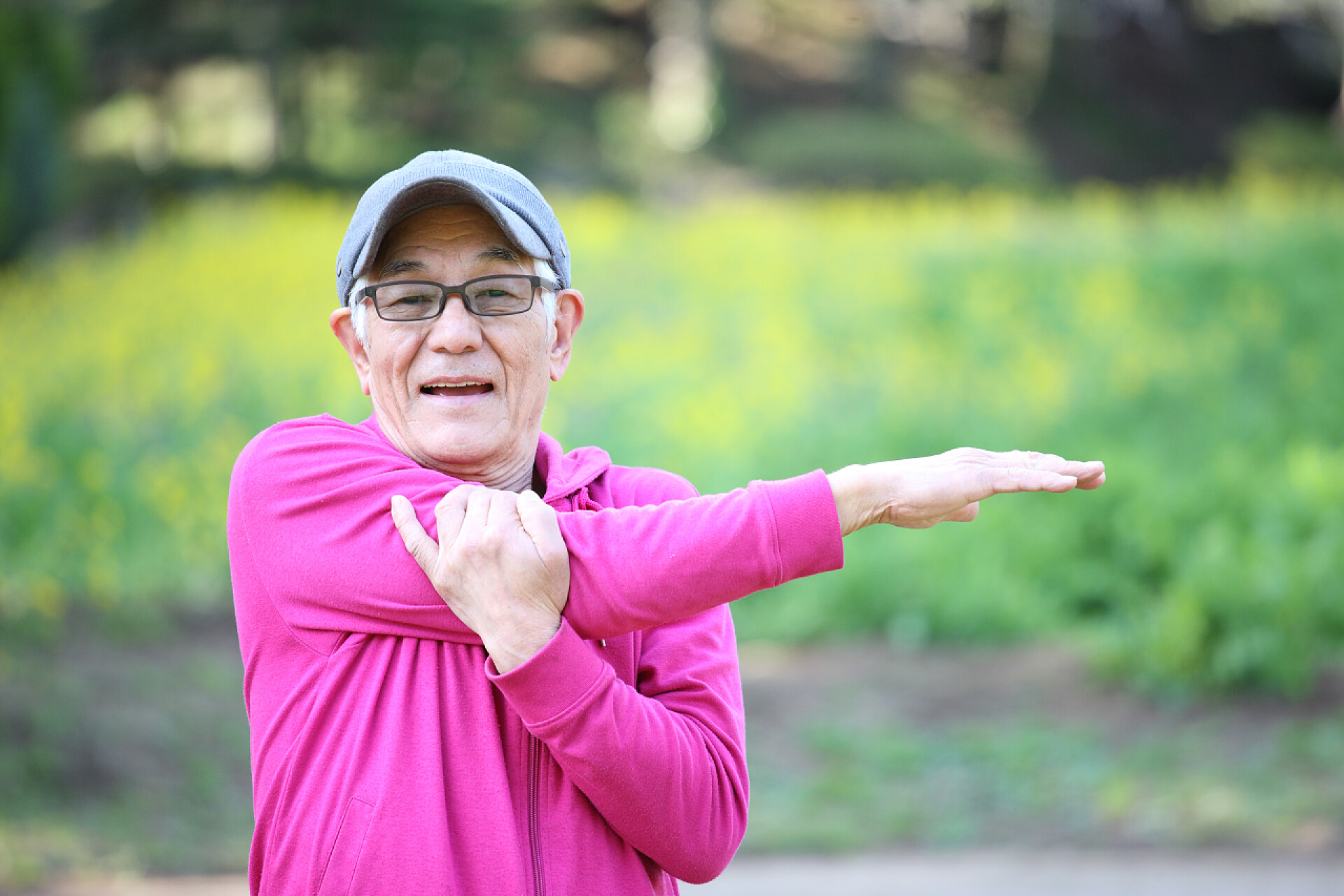 老人在户外伸臂运动身穿粉色长袍的日本老人在户外伸臂