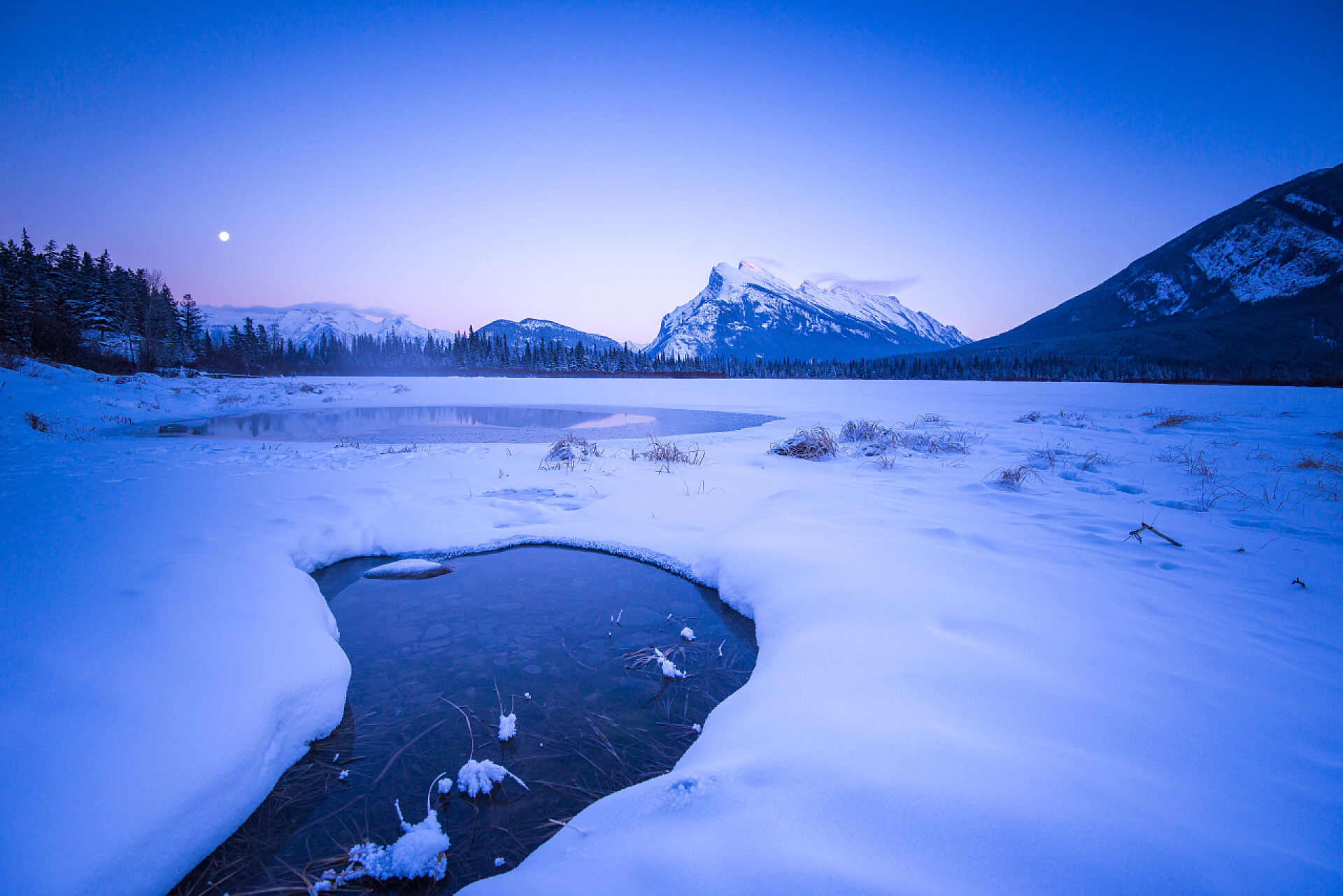 冬天傍晚结冰的湖面和远处的雪山秀丽的山水和水晶湖景