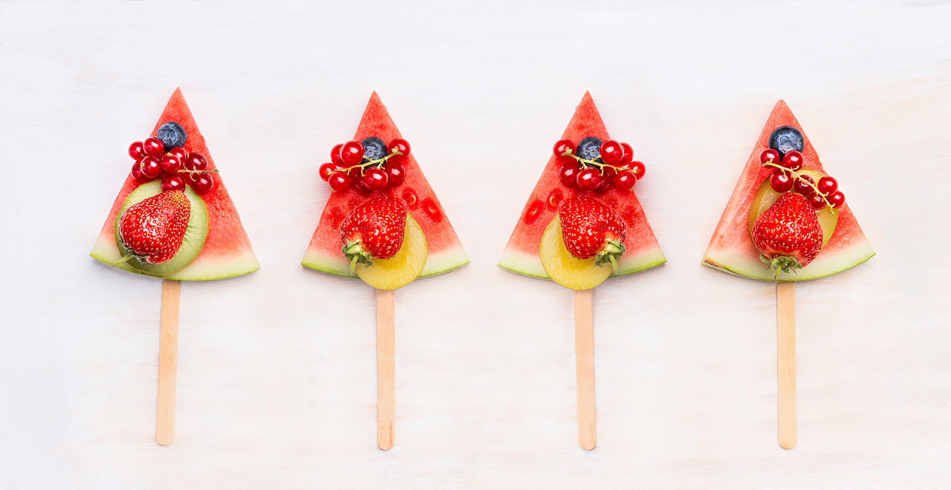 西瓜片上的水果和浆果西瓜片爆米花与水果和浆果的白色木制背景，顶部视图。健康食品和素食概念