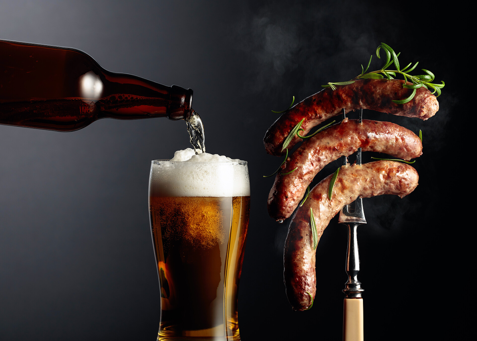 黑色背景中叉子上的香肠和一杯啤酒啤酒和烤巴伐利亚香肠与迷迭香。叉子上的香肠撒满了迷迭香.复制空间.