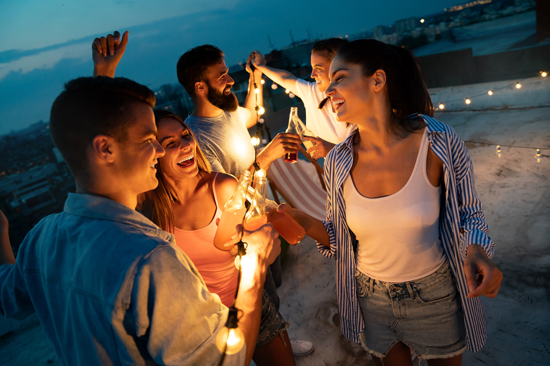 傍晚在屋顶开派对的年轻人和年轻的朋友们玩得开心，在屋顶派对上玩得开心