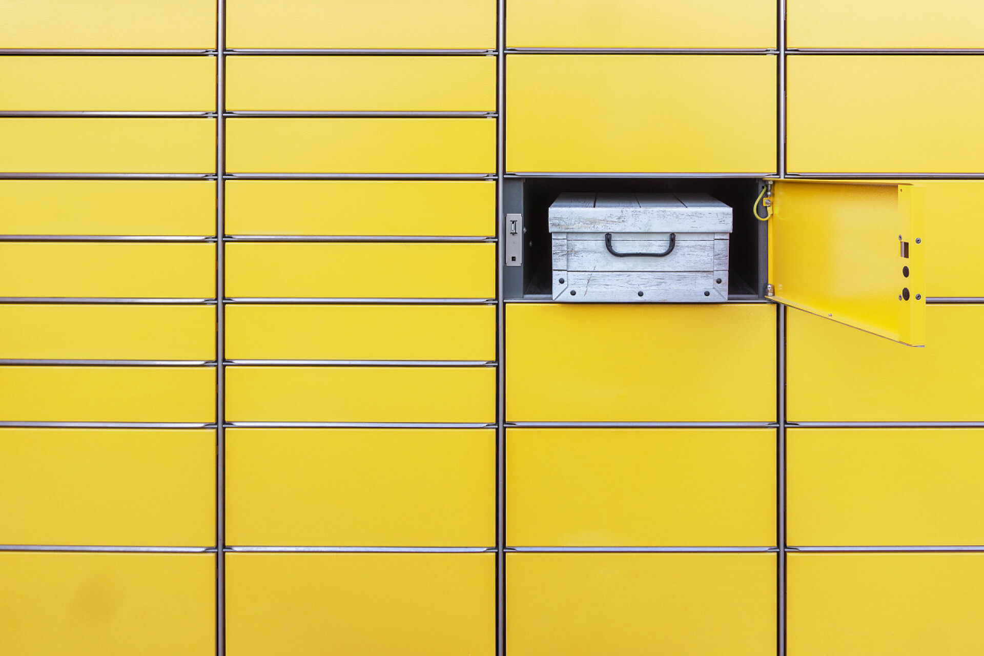 包裹在黄色的快递柜中特写收到的包裹装在自动自助邮政终端机的开箱内。以黄色自动自助服务岗位终端装运。用开箱装包裹的邮筒墙壁的简约观点