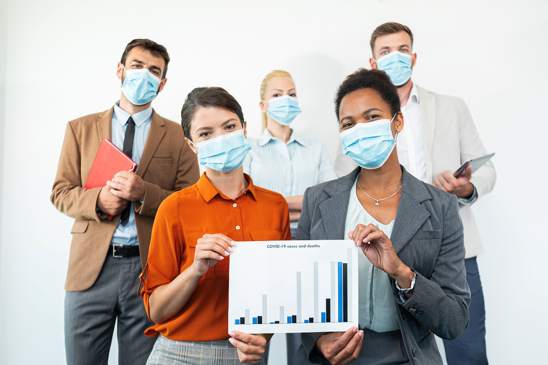 举着柱状统计图的戴口罩的年轻学生们一组学生正在看着摄像机，戴着面具，并且因为头颈类动物的出现而显示出统计数字