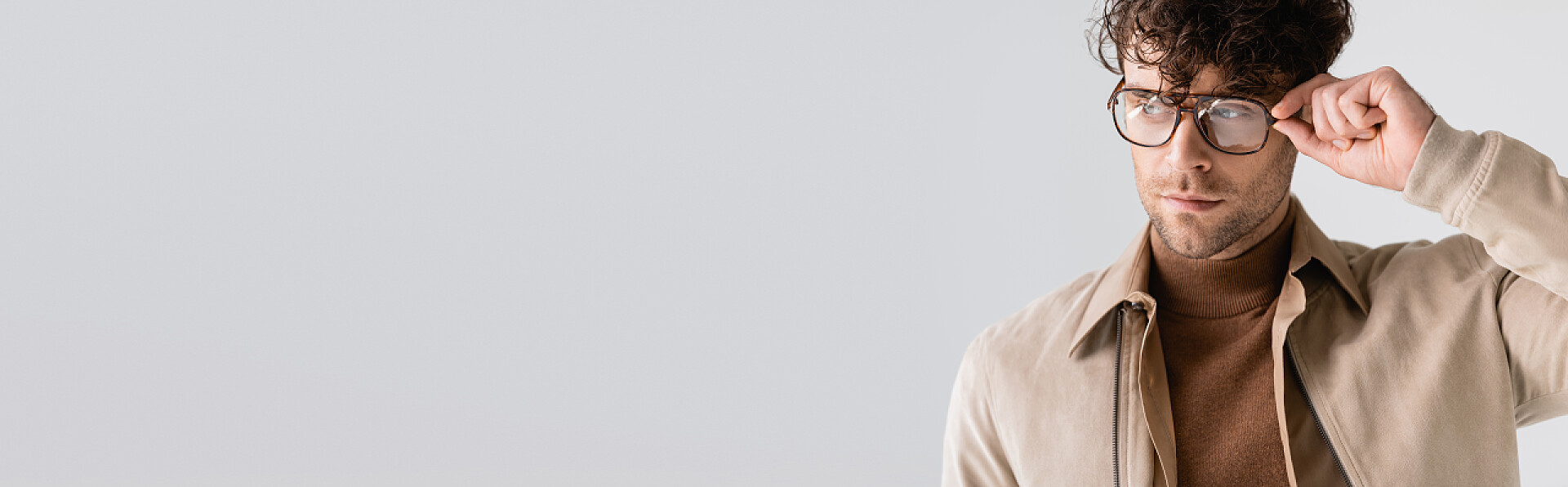 手扶眼镜看向远处的时髦男模特肖像水平线图片,时尚英俊的男人触摸眼镜,凝视着远方的灰色