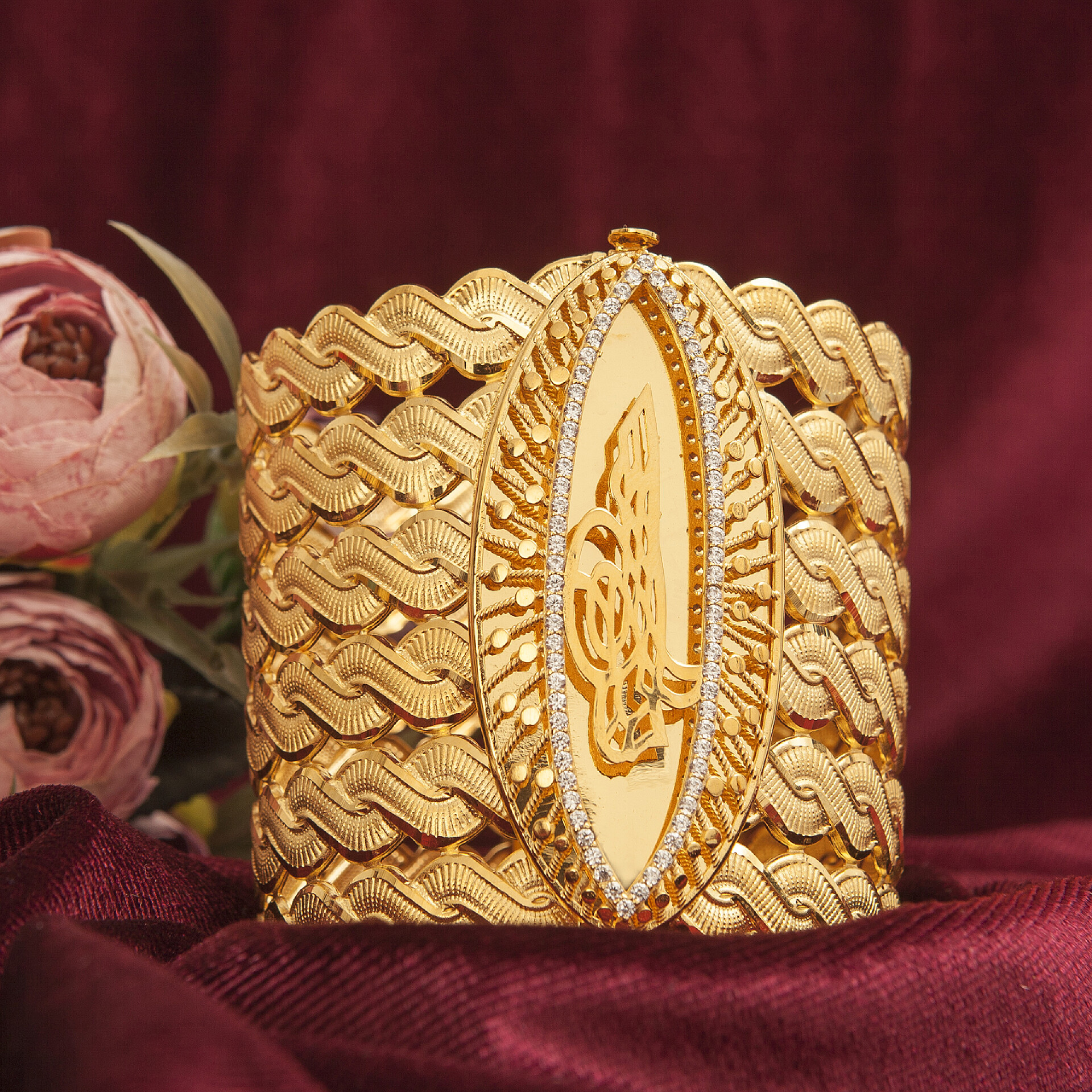 桌子上的金色镯子特写红色天鹅绒织物上的女用金饰品