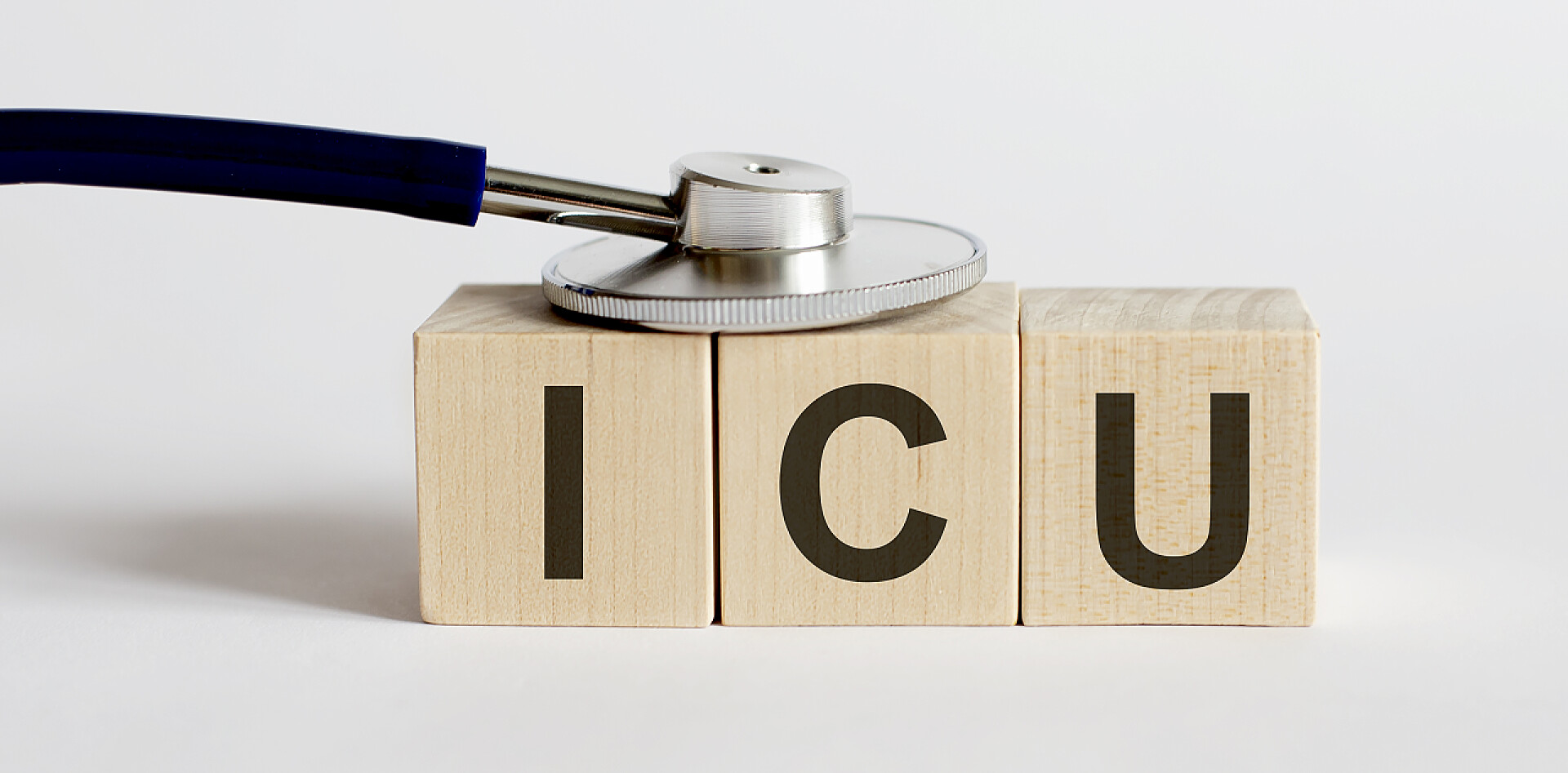 木块上的ICU的字母和医用听诊器白色背景下带木块ICU的医用听诊器