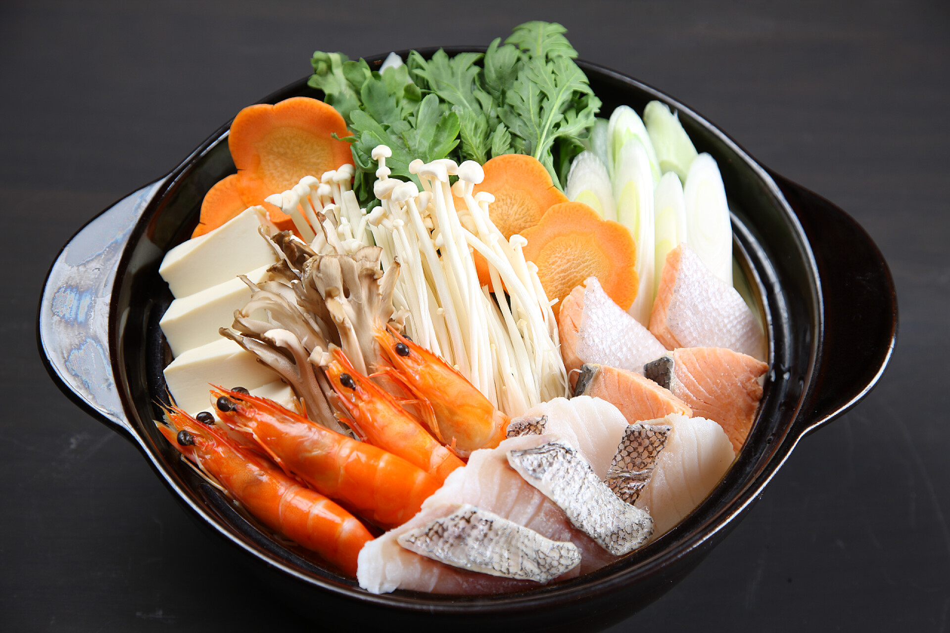 黑色桌子上黑碗里的海鲜例如：海味相扑手火锅