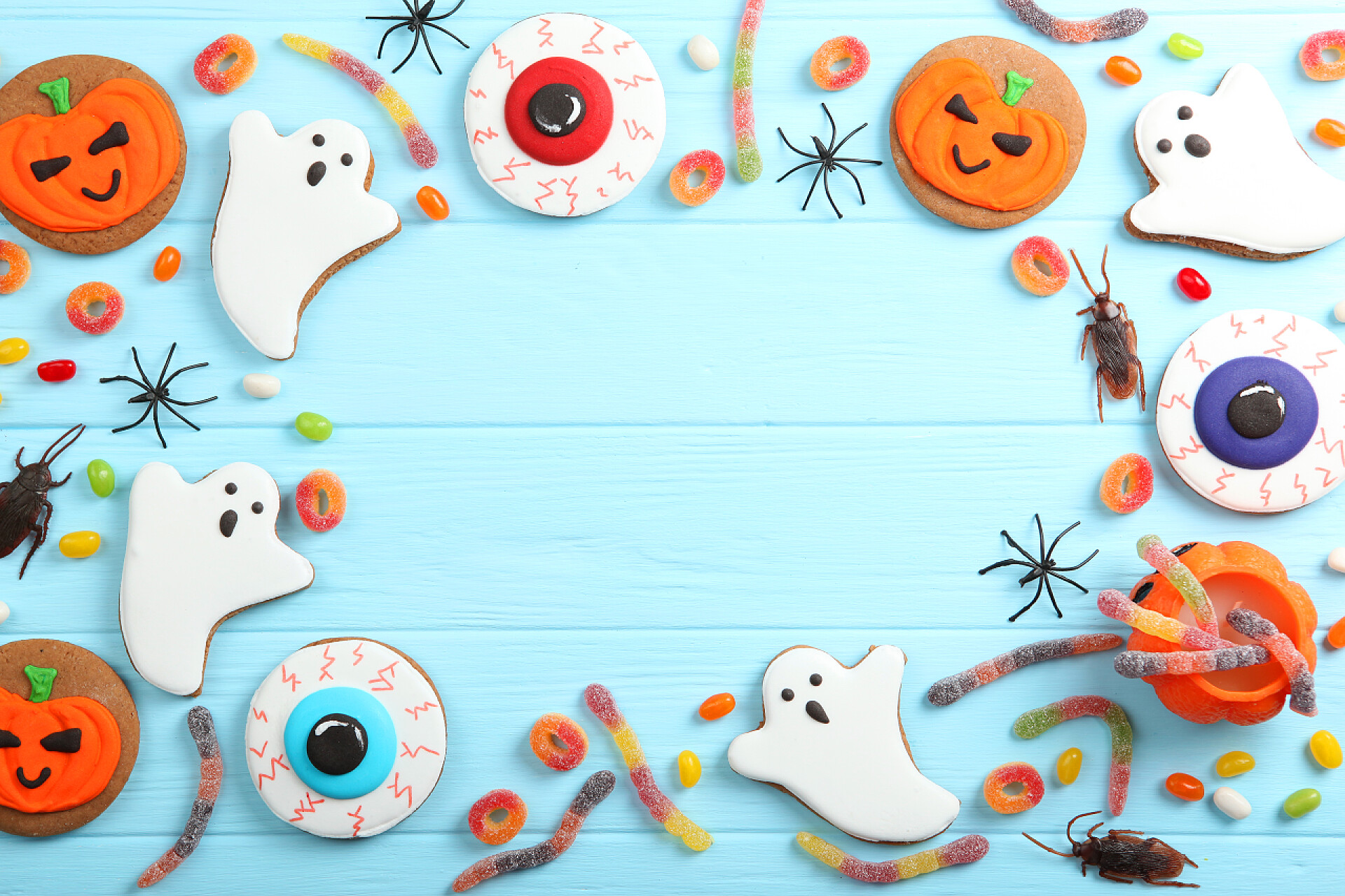 蓝色桌子上的万圣节用品Halloween background with gingerbread and other sweets top view with place for text