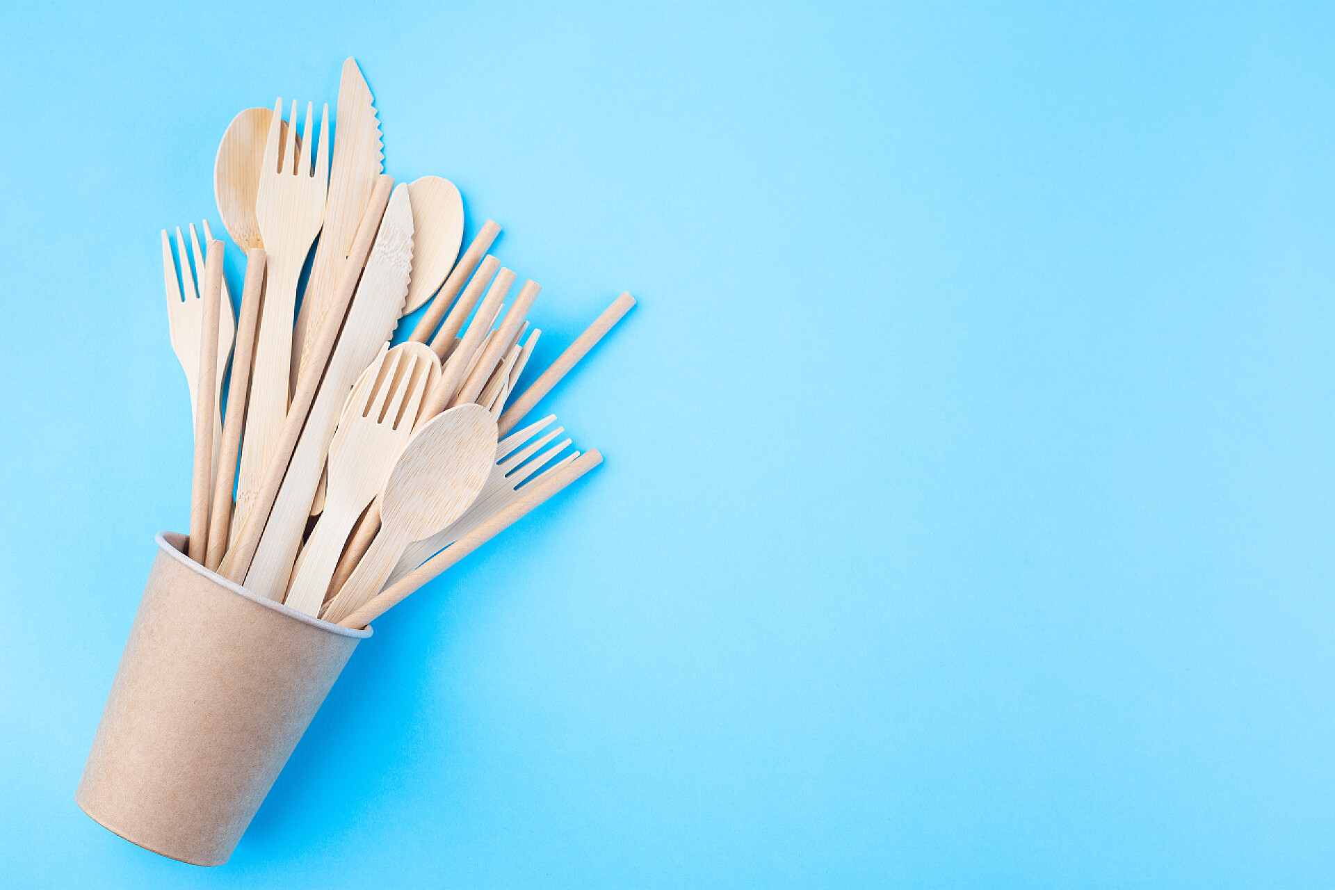 蓝色桌子上的纸质餐具蓝色底座上的不同类型的木制和纸制器皿，零废物或无塑料概念，水平、复制空间