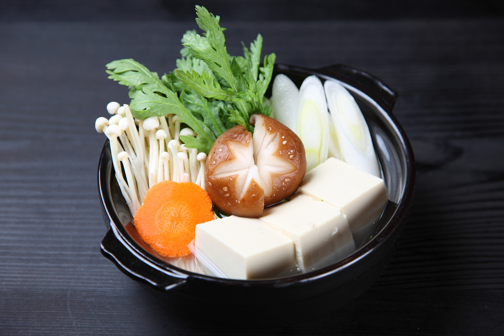 黑色桌子上黑碗里的米线带蘑菇火锅的烤肉卷 