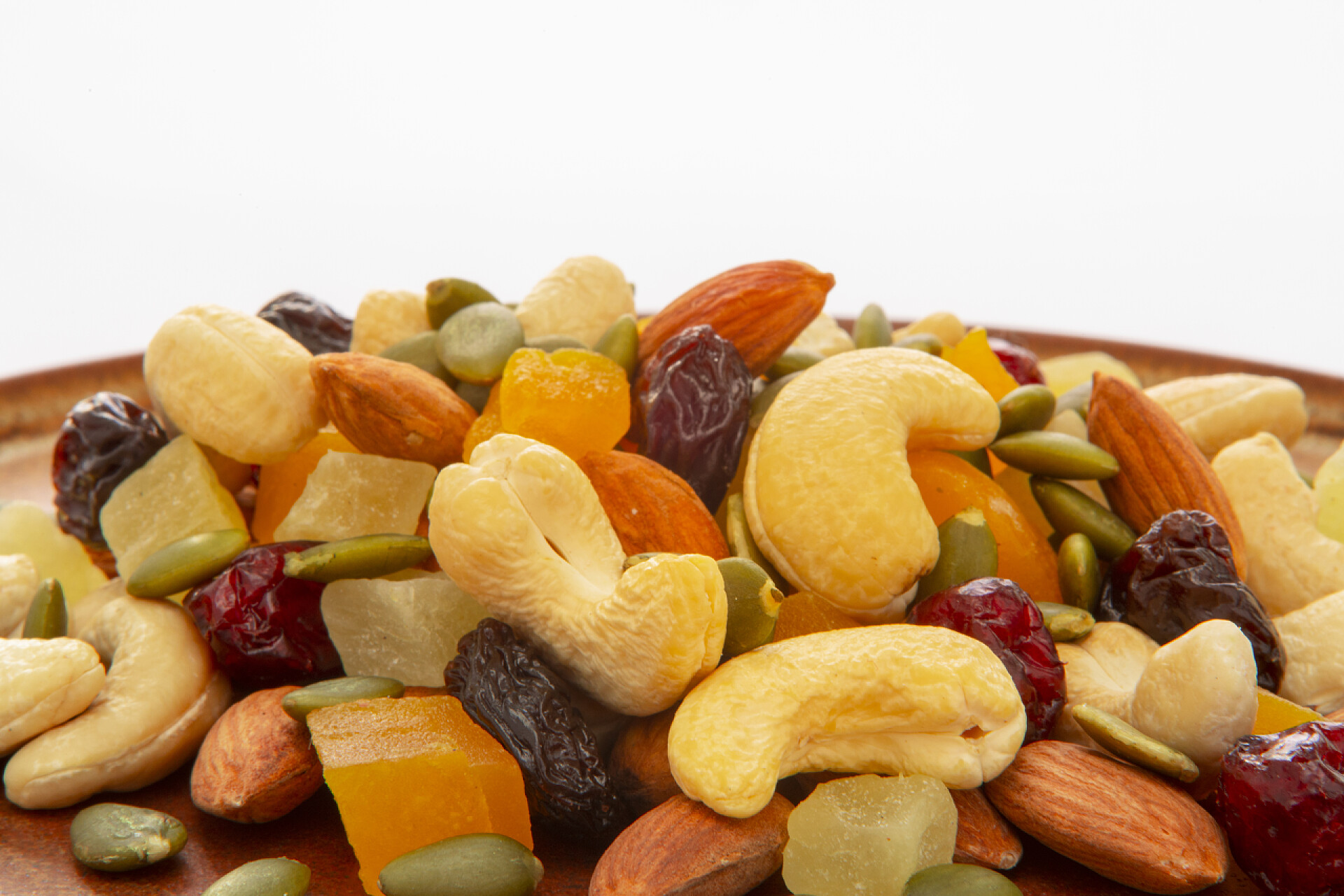 白色背景前的坚果和果干盘子里有营养的混合坚果