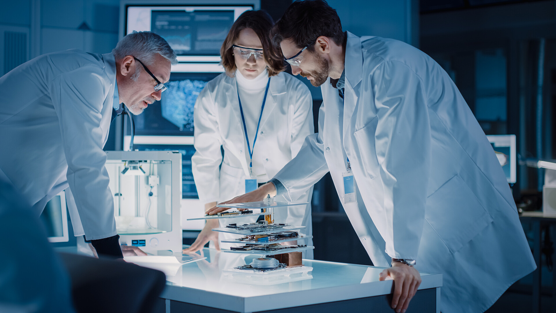 几位在研究机器人开发的工程师在工业设计实验室、专业使用显微镜、个人电脑设计工作、玻璃白板上的研究人员写作、 3D打印机和母板开发团队中拍摄