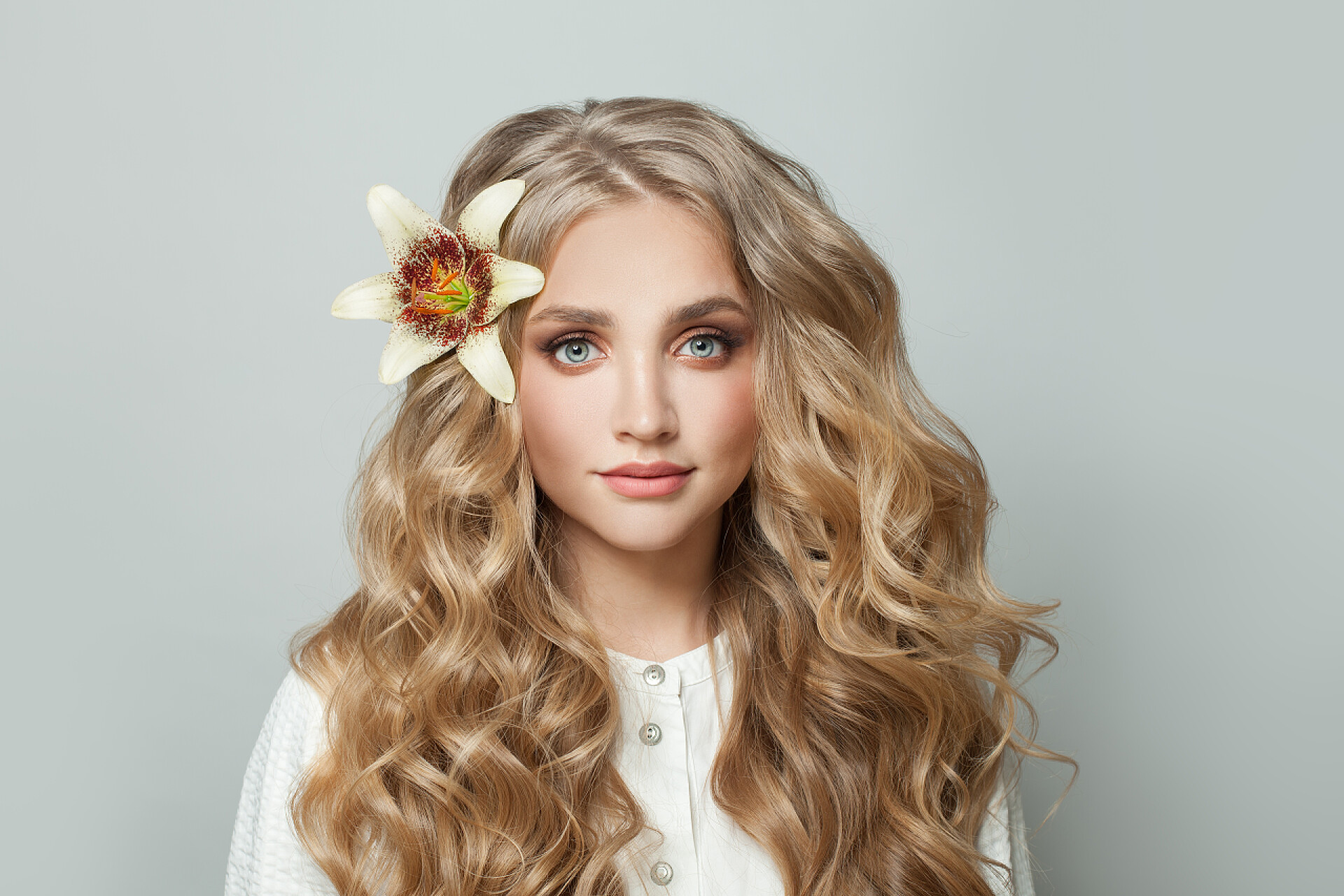 灰色背景墙卷头发的女人头发长、头戴花的年轻貌美女人